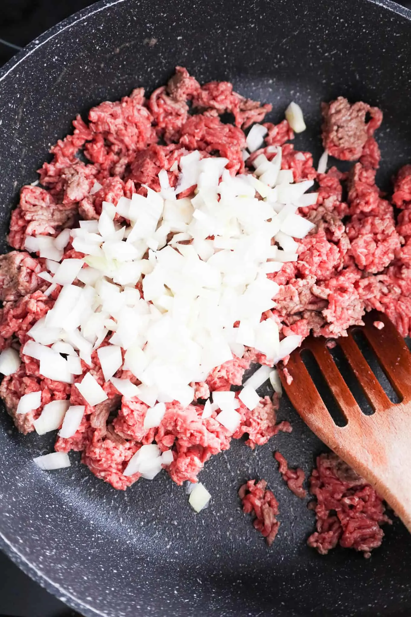 diced onions added to a skillet with ground beef