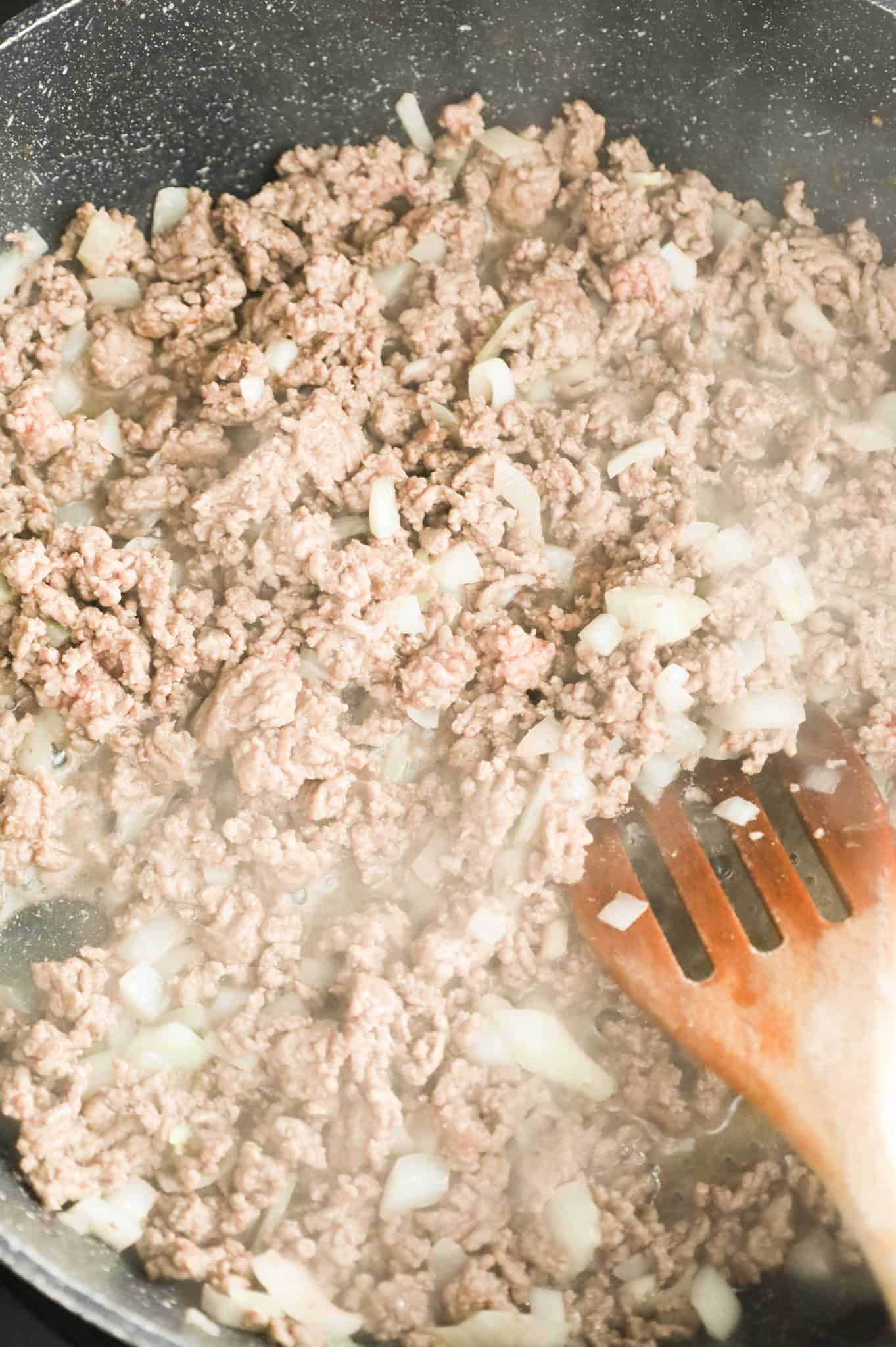 ground beef and diced onions cooking in a skillet