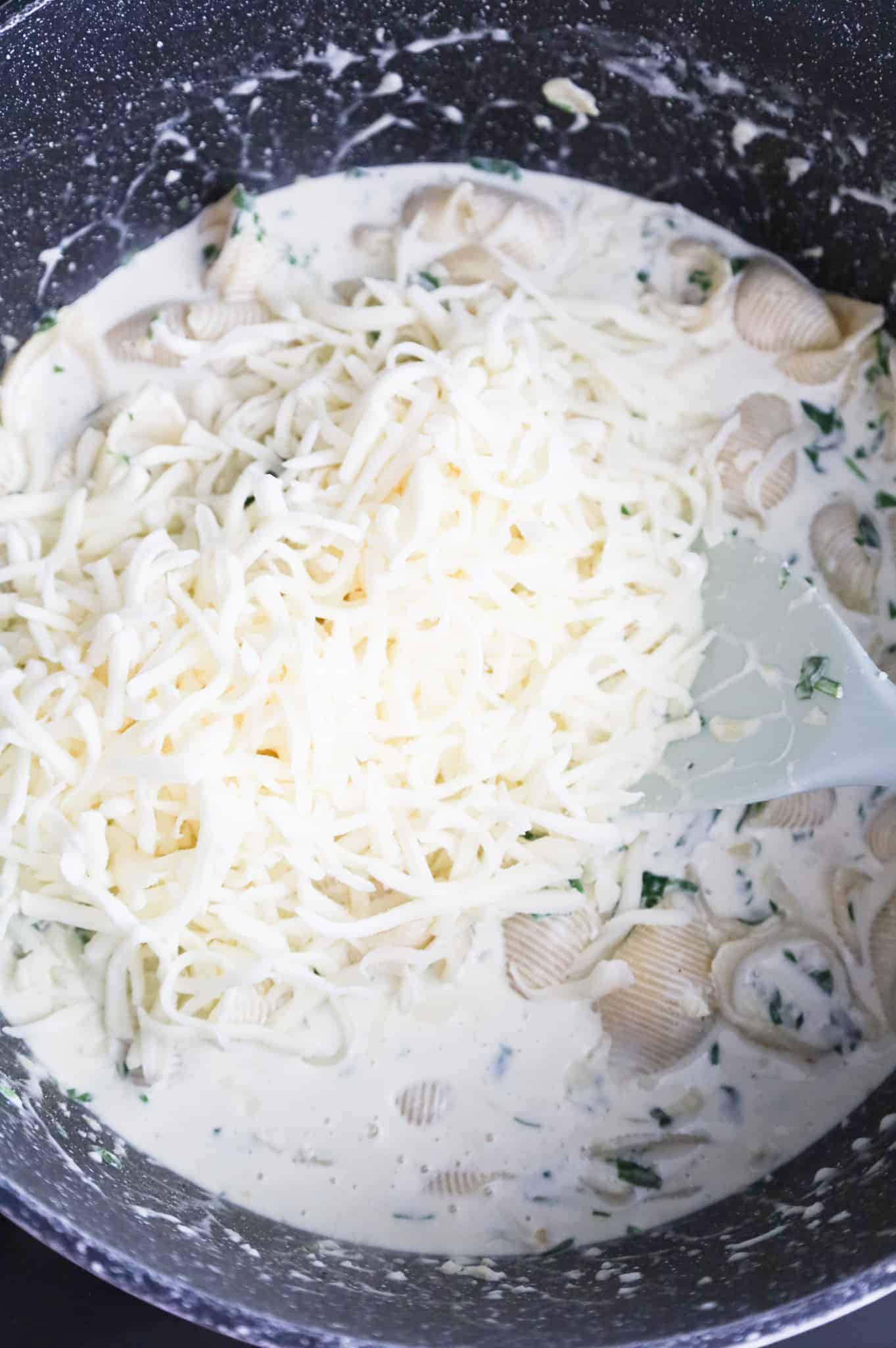 shredded mozzarella added to a post with creamy pasta