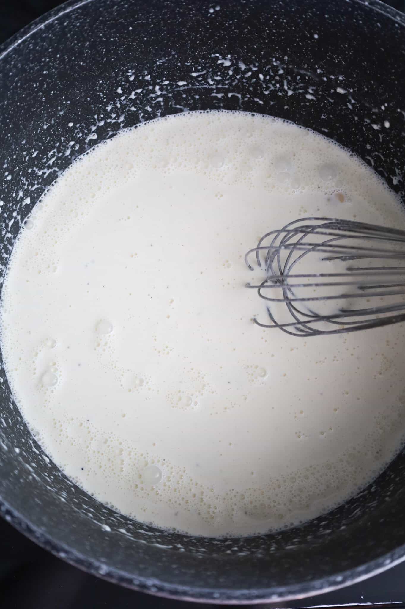 whisking cream sauce mixture in a pot