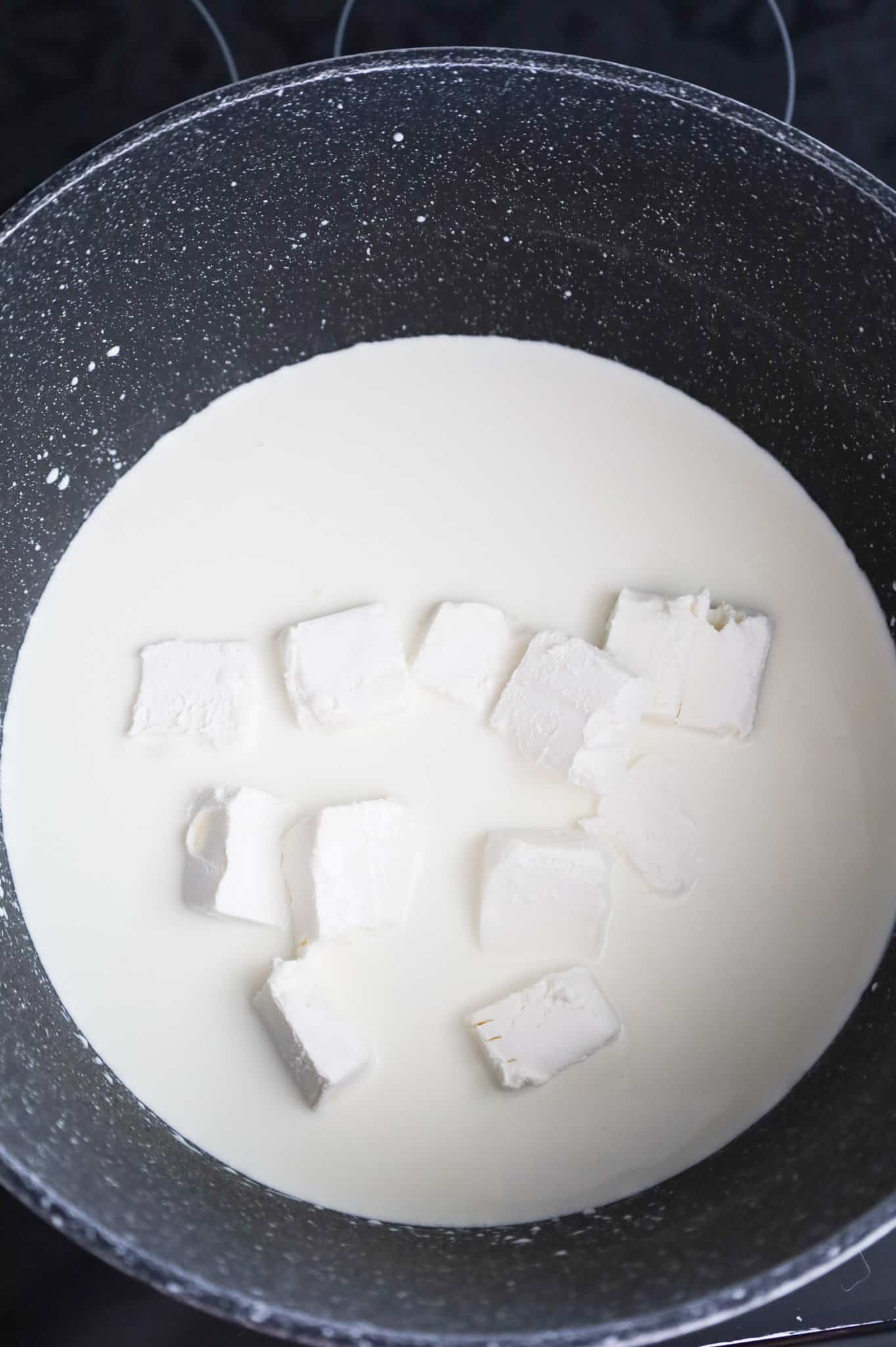 cubes of cream cheese added to pot with heavy cream