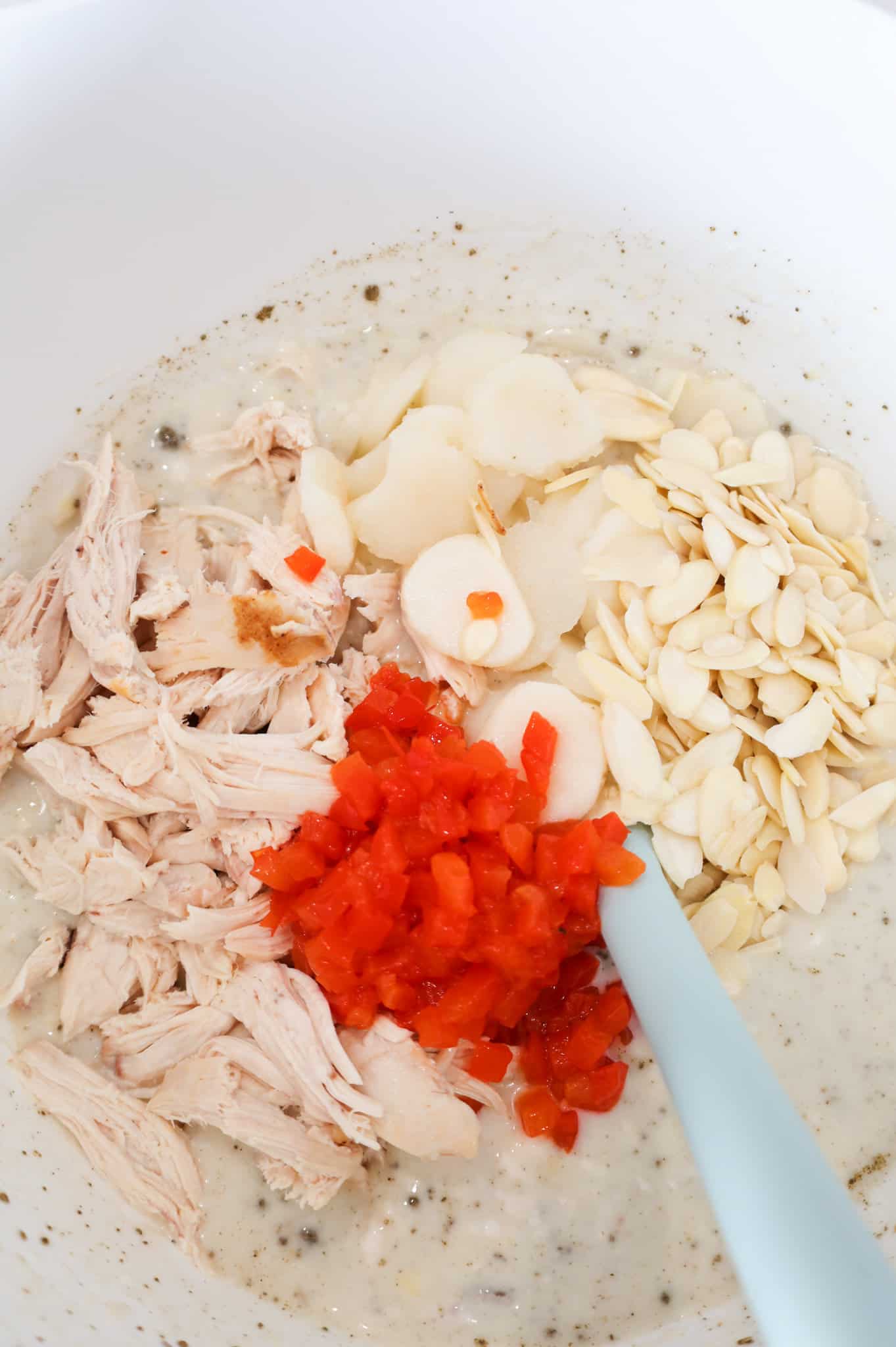 diced pimentos, shredded chicken, sliced water chestnuts and sliced almonds on top of cream soup mixture in a mixing bowl