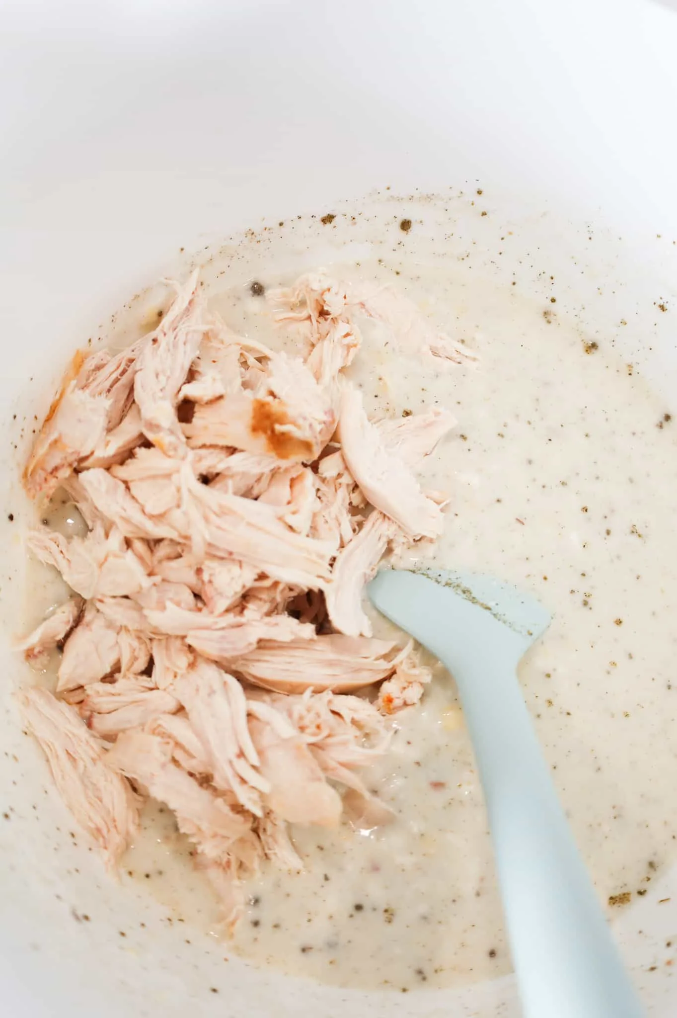 shredded chicken added to mixing bowl on top of cream soup mixture