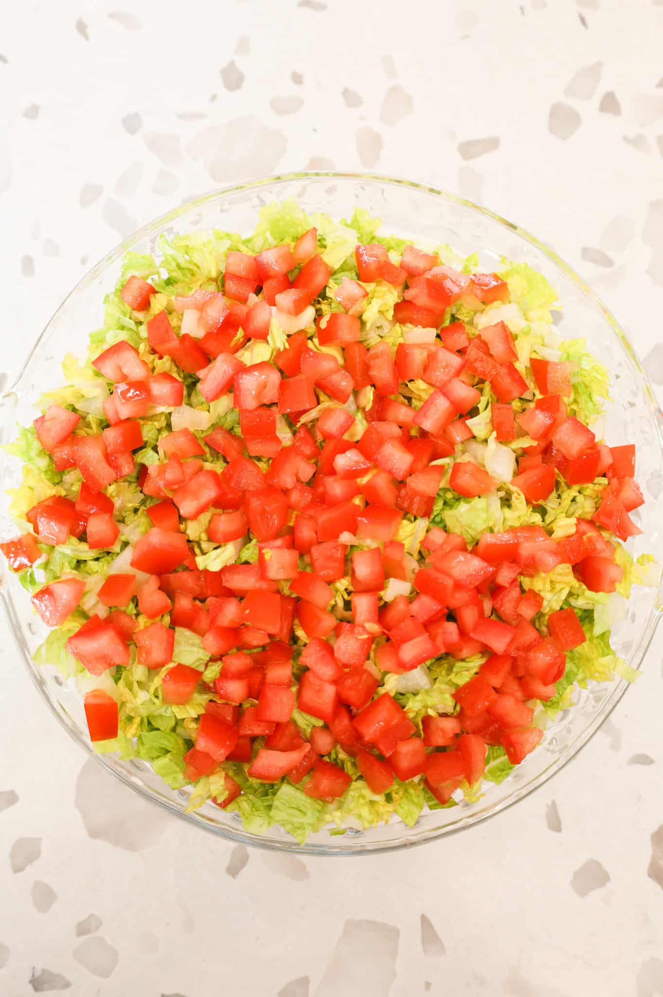 diced tomatoes and chopped lettuce on top of mayo mixture in a pie plate