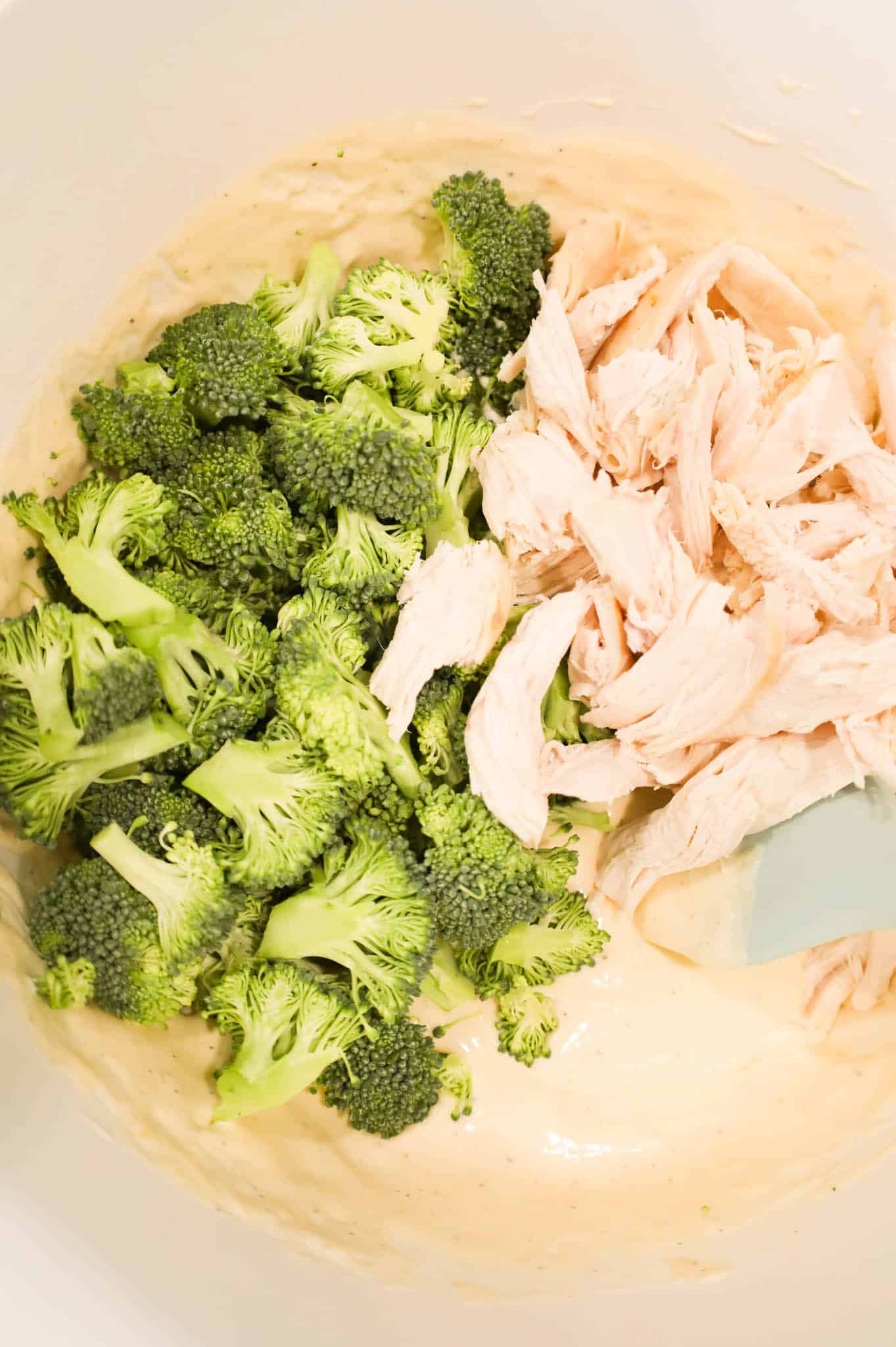 broccoli florets and shredded chicken on top of cream soup mixture in a bowl