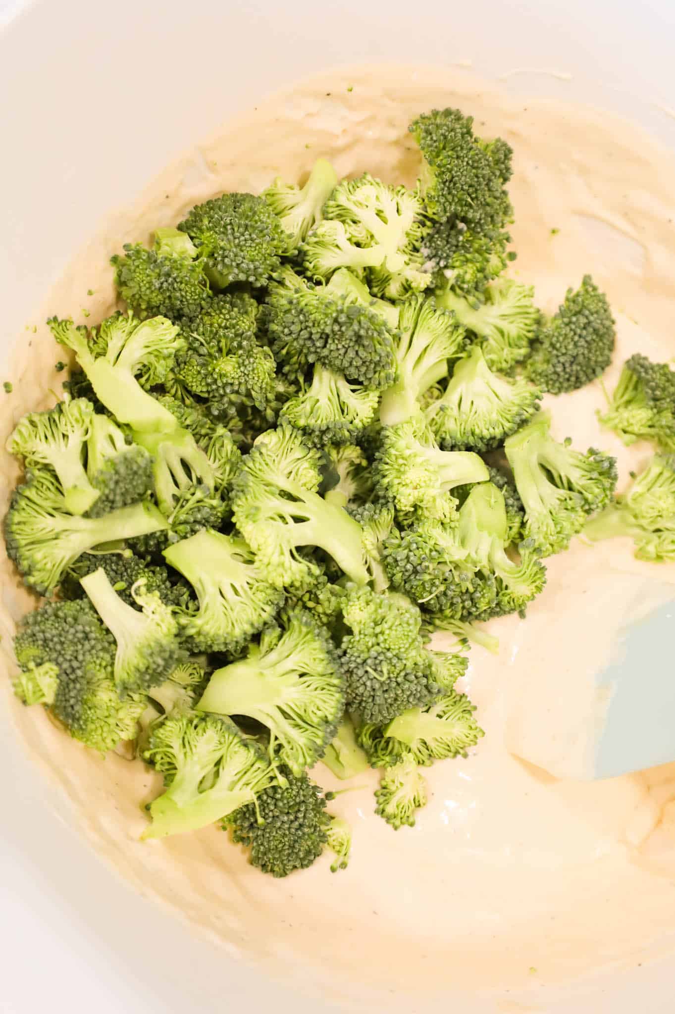 broccoli florets added to a bowl with a creamy soup mixture