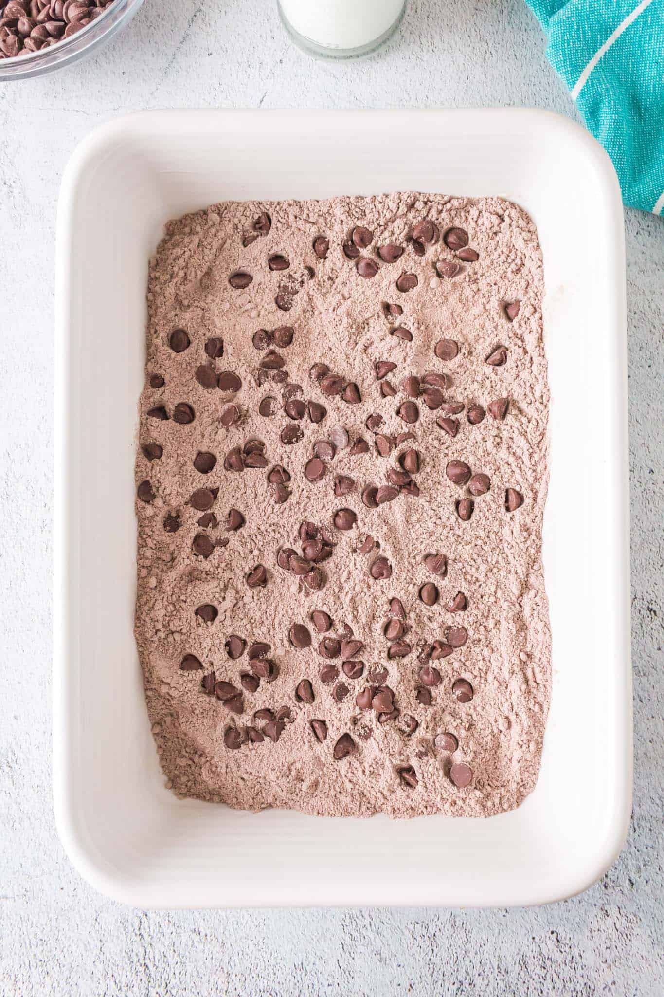 chocolate chips on top of dry chocolate cake mix and pudding mix in a baking dish