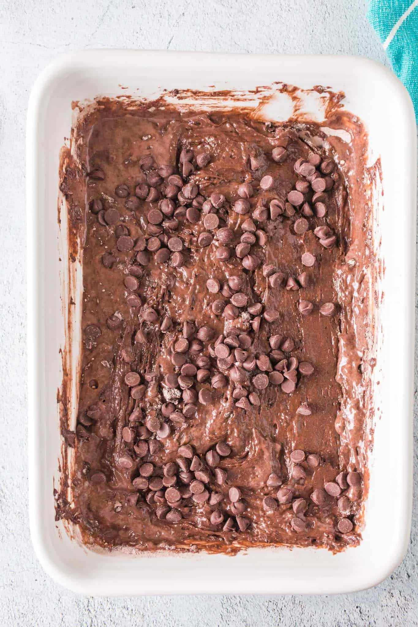 sprinkle chocolate chips on top of chocolate cake batter in a baking dish