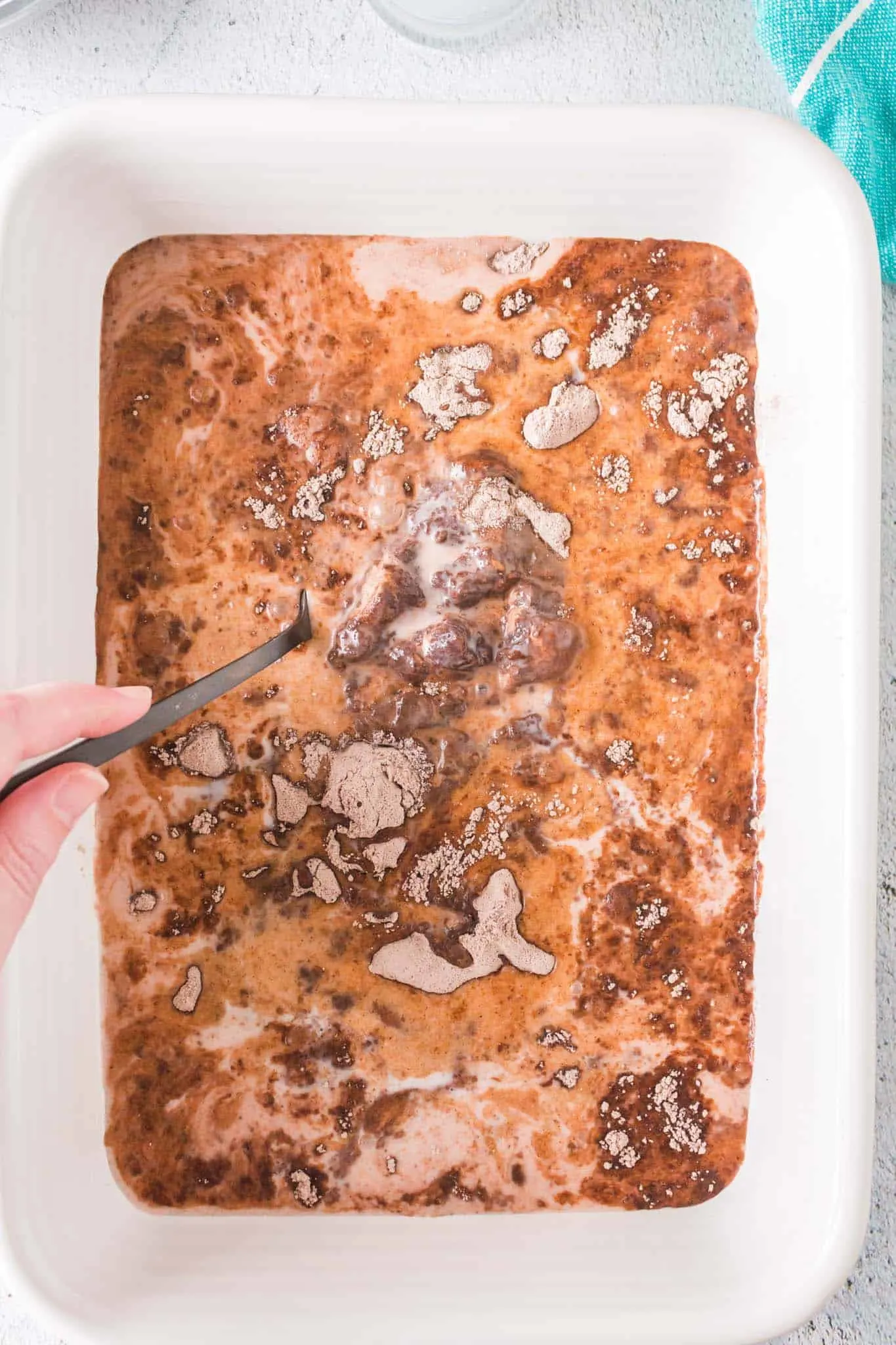 stirring milk, cake mix and pudding mix together in a baking dish