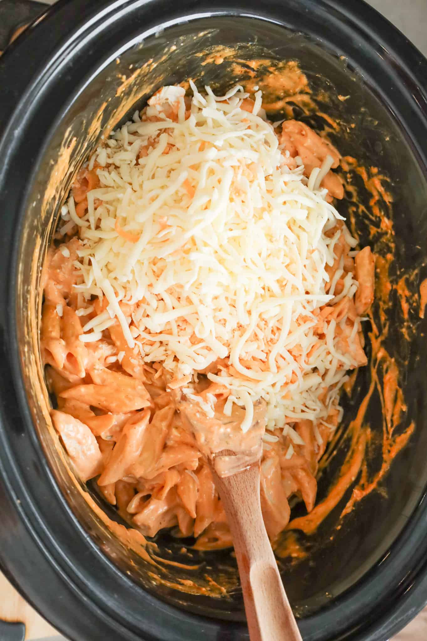 shredded cheese added to crock pot with Buffalo chicken pasta