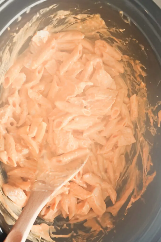 Buffalo chicken pasta being stirred in a Crock Pot