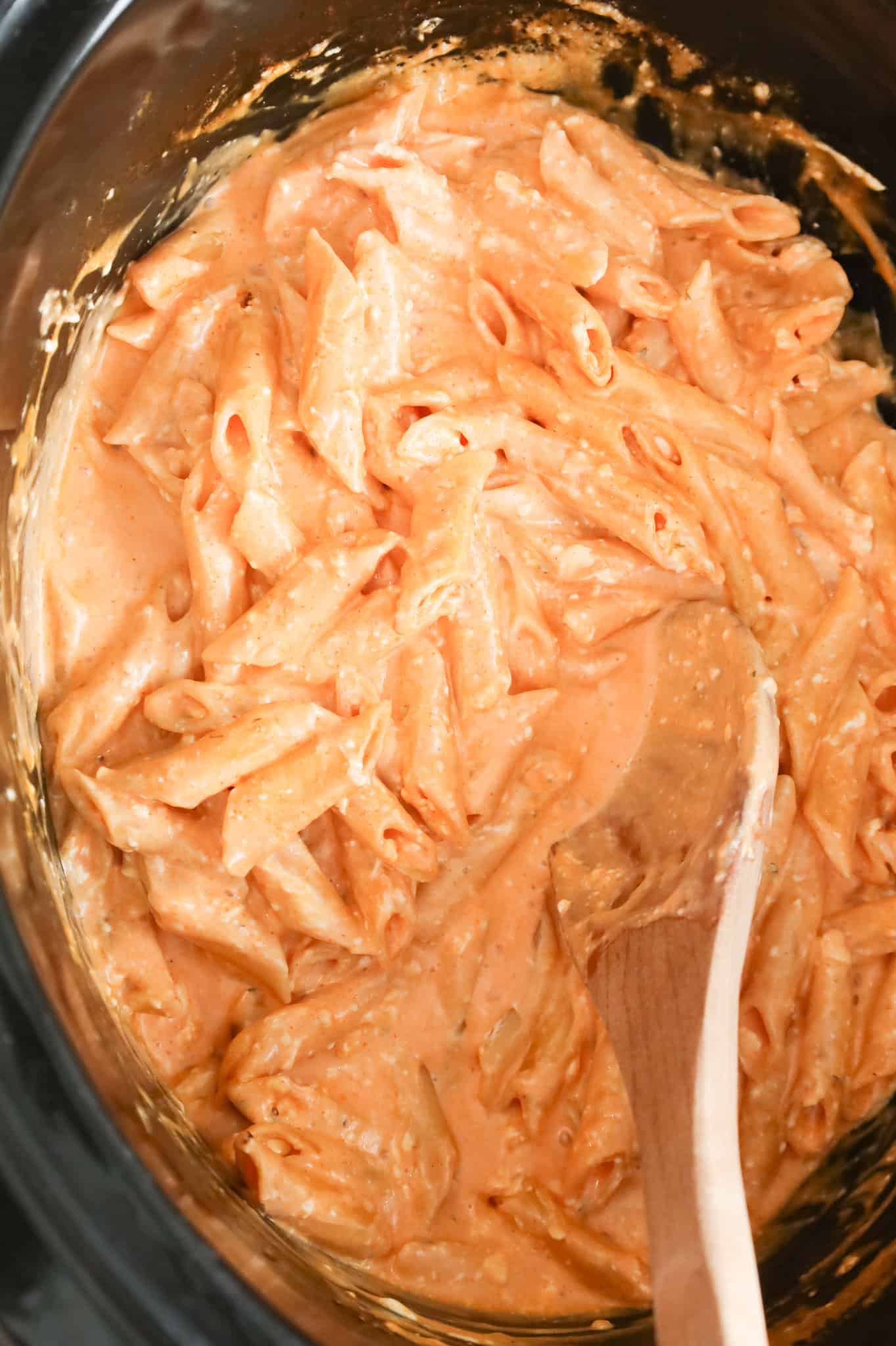 Buffalo chicken pasta being stirred in a crock pot