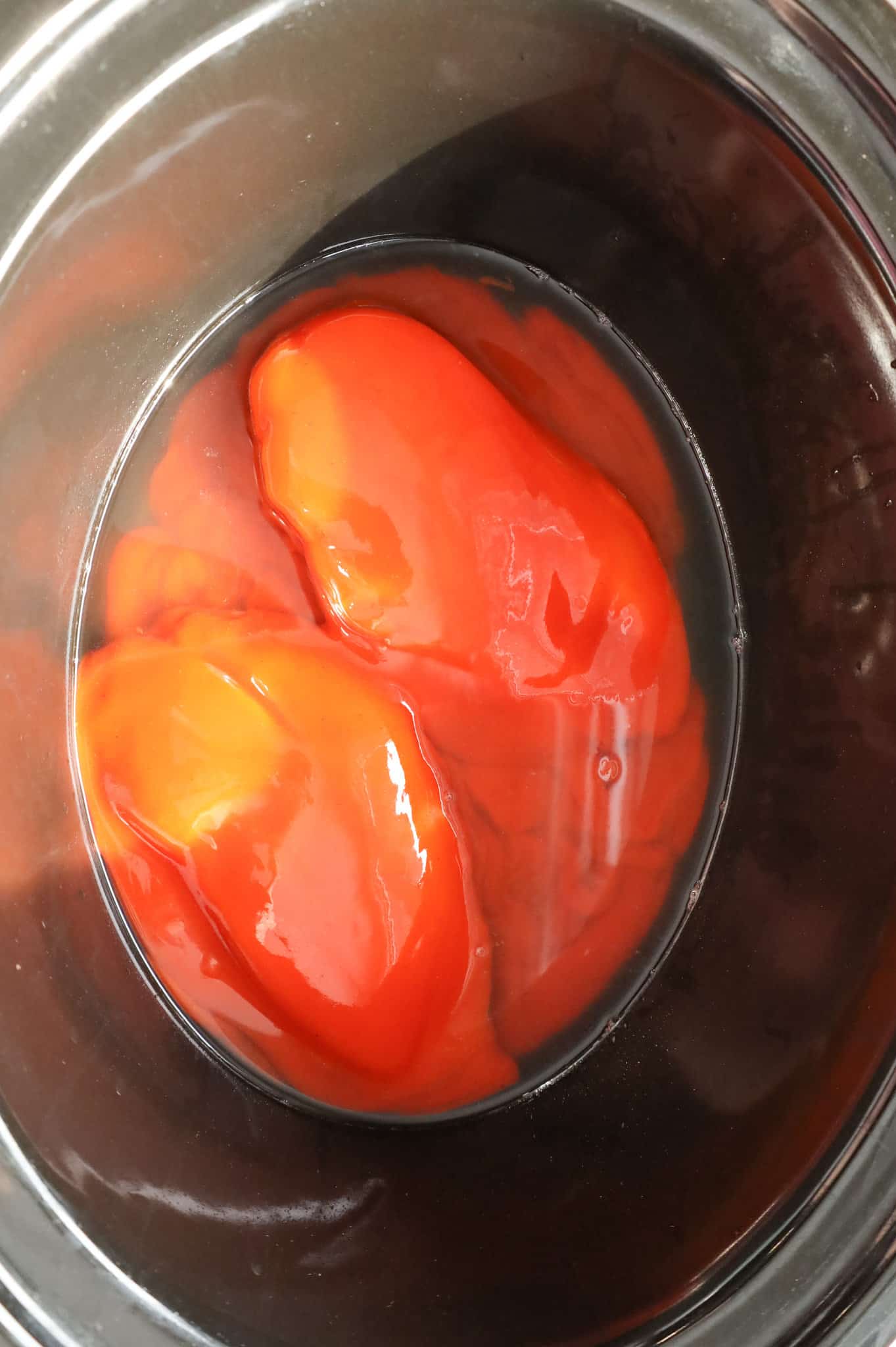 Buffalo sauce and chicken broth on top of chicken breasts in a Crock Pot