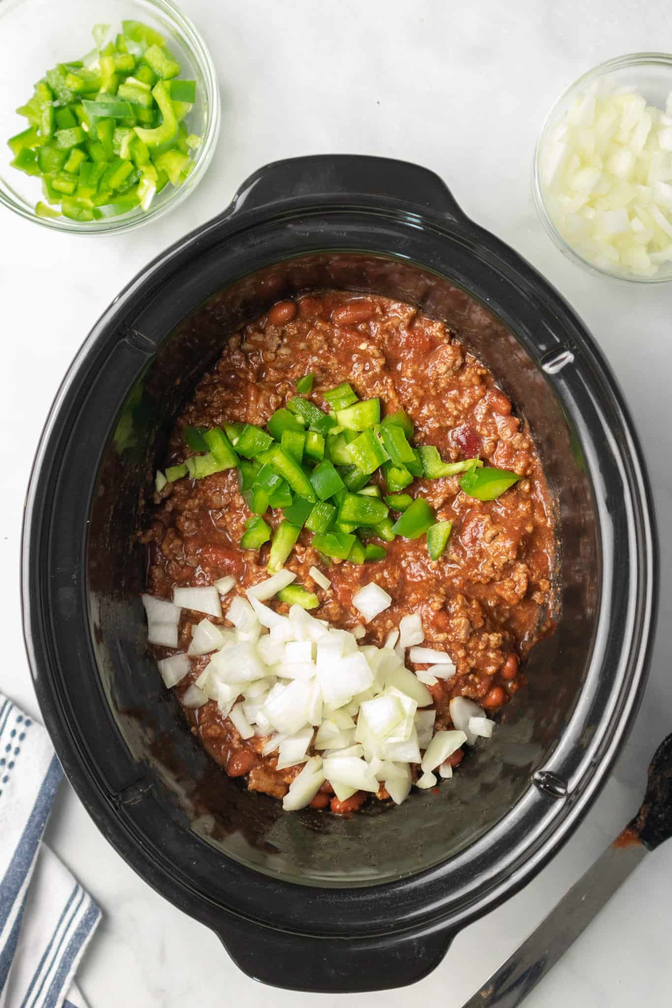 diced green peppers and diced onions added to crock pot with chili ingredients