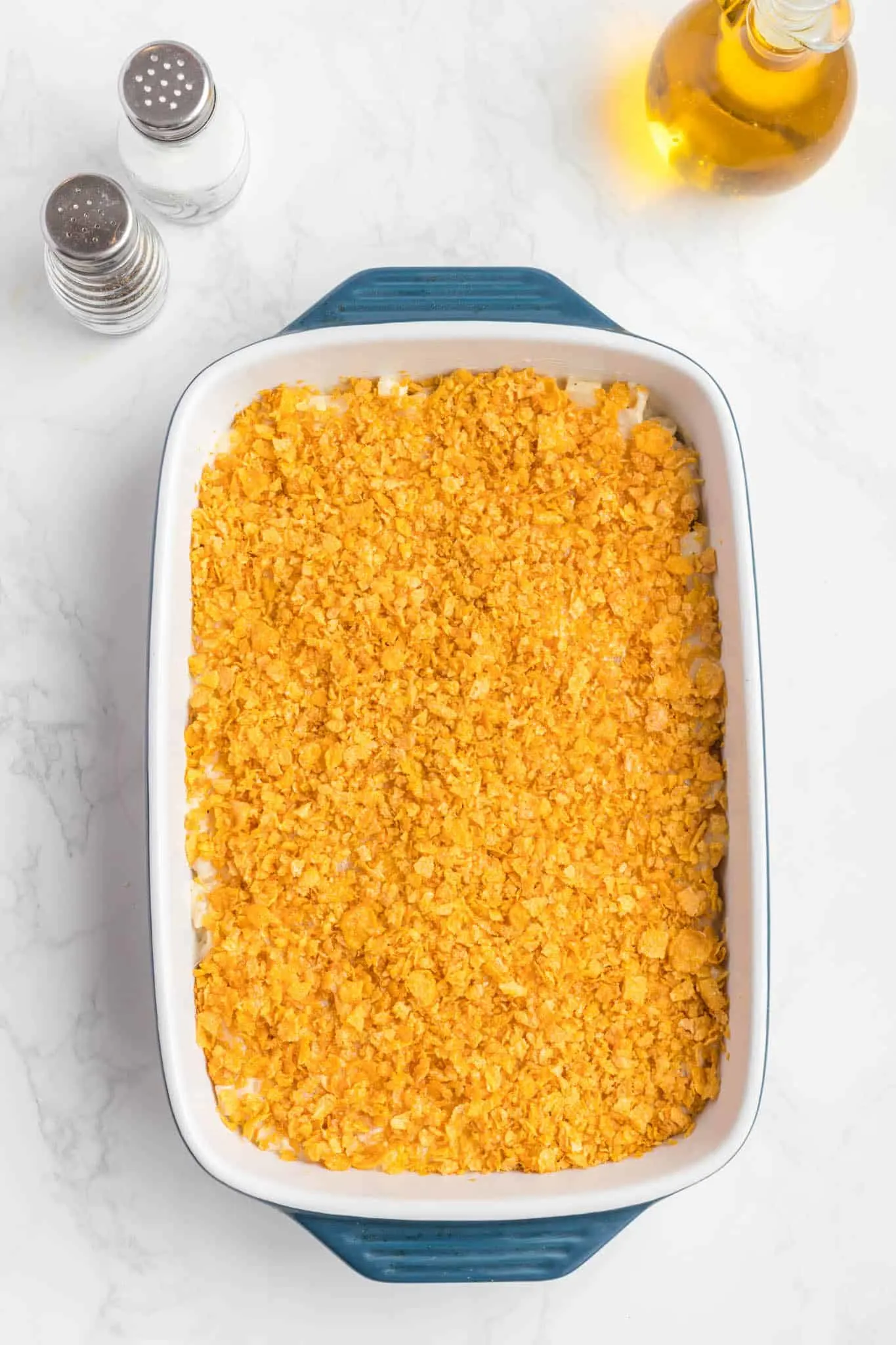 crushed cornflake mixture on top of potatoes in a baking dish