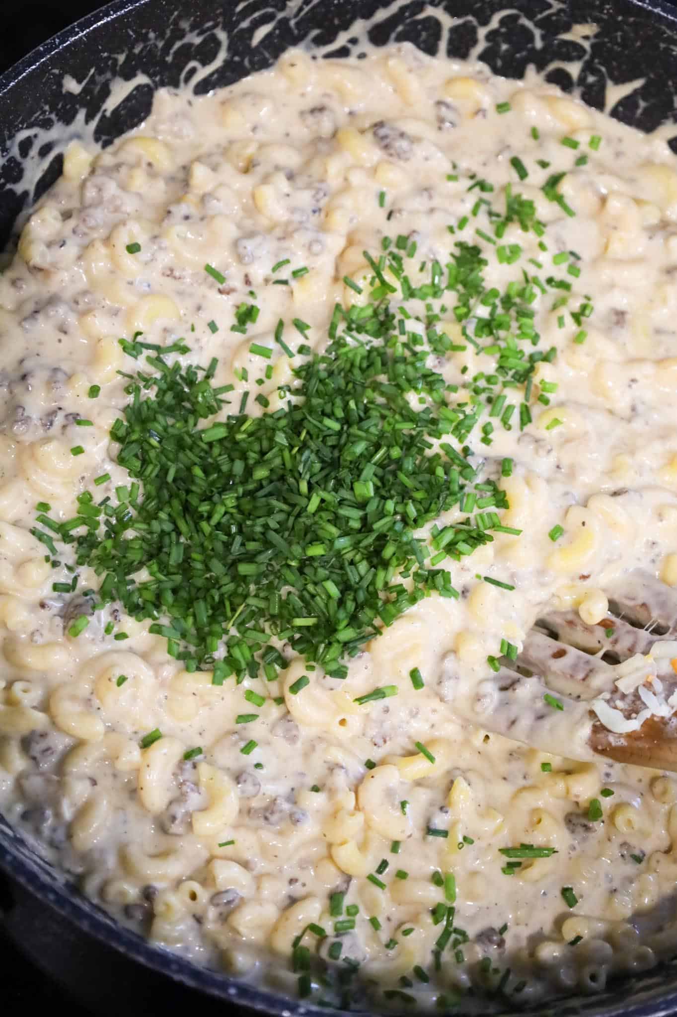 chopped chives on top of cheesy macaroni in a skillet