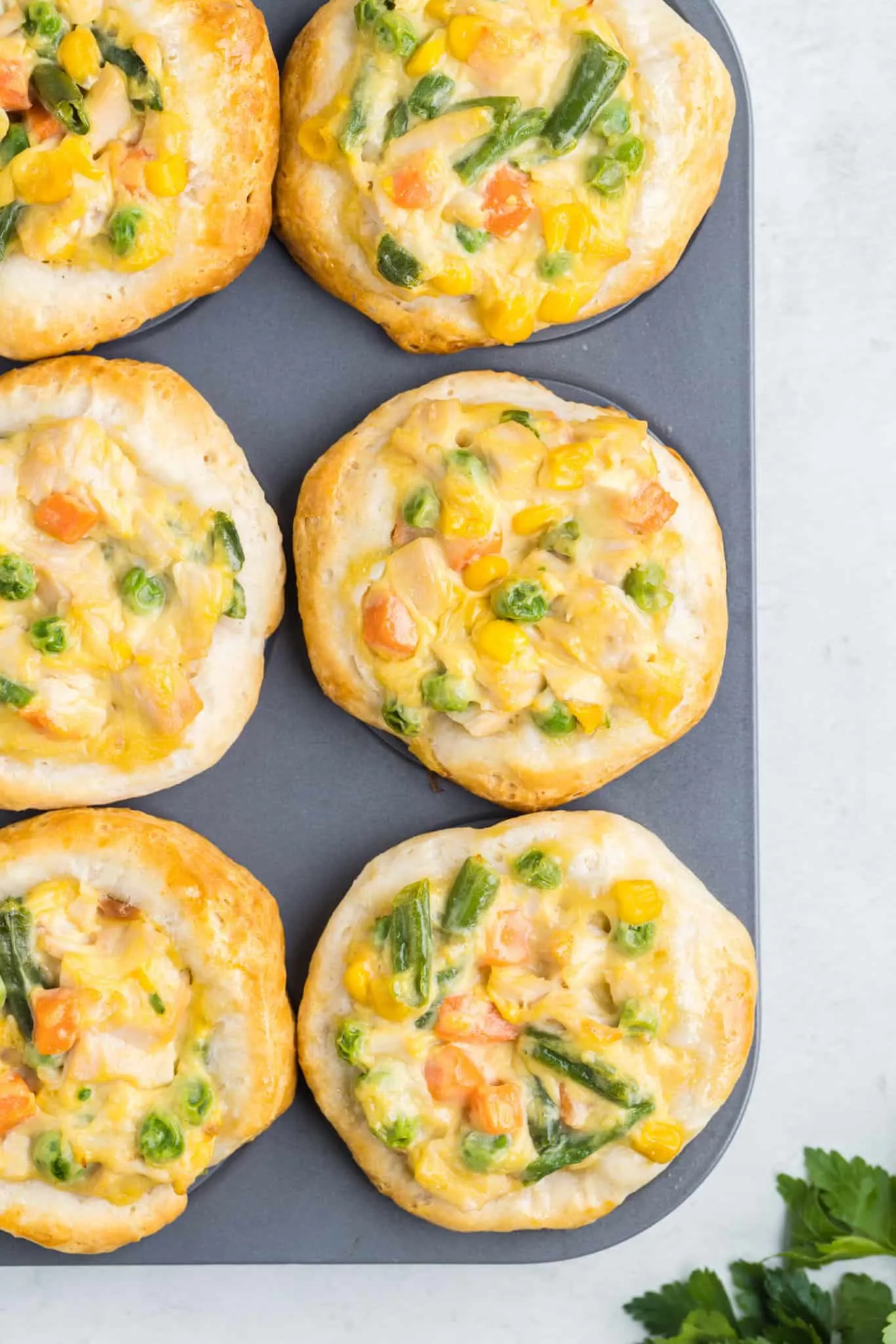 Mini Chicken Pot Pies are an easy dinner recipe using precooked chicken, frozen mixed vegetables, cream of chicken soup and Pillsbury refrigerated biscuits.