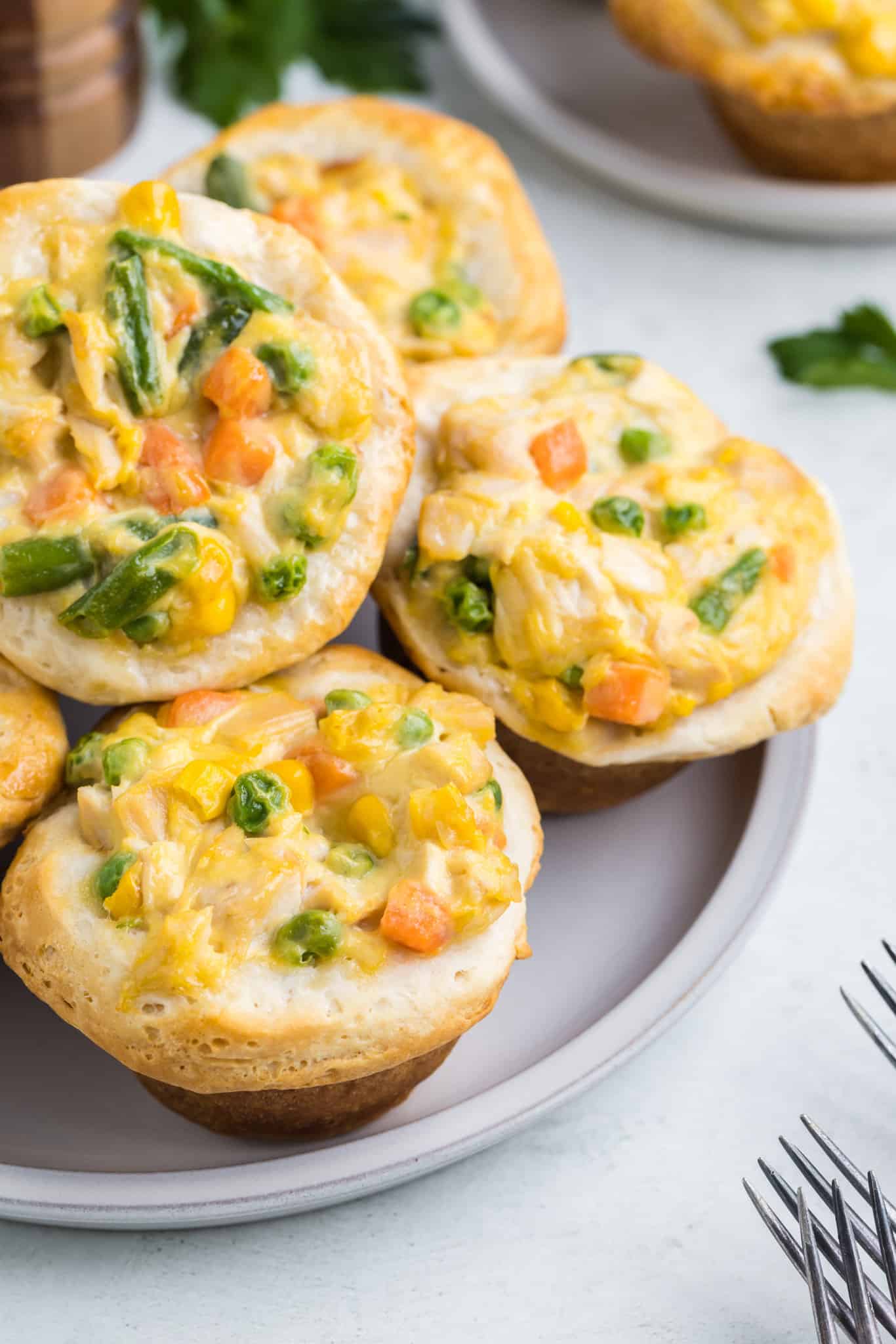 Mini Chicken Pot Pies are an easy dinner recipe using precooked chicken, frozen mixed vegetables, cream of chicken soup and Pillsbury refrigerated biscuits.