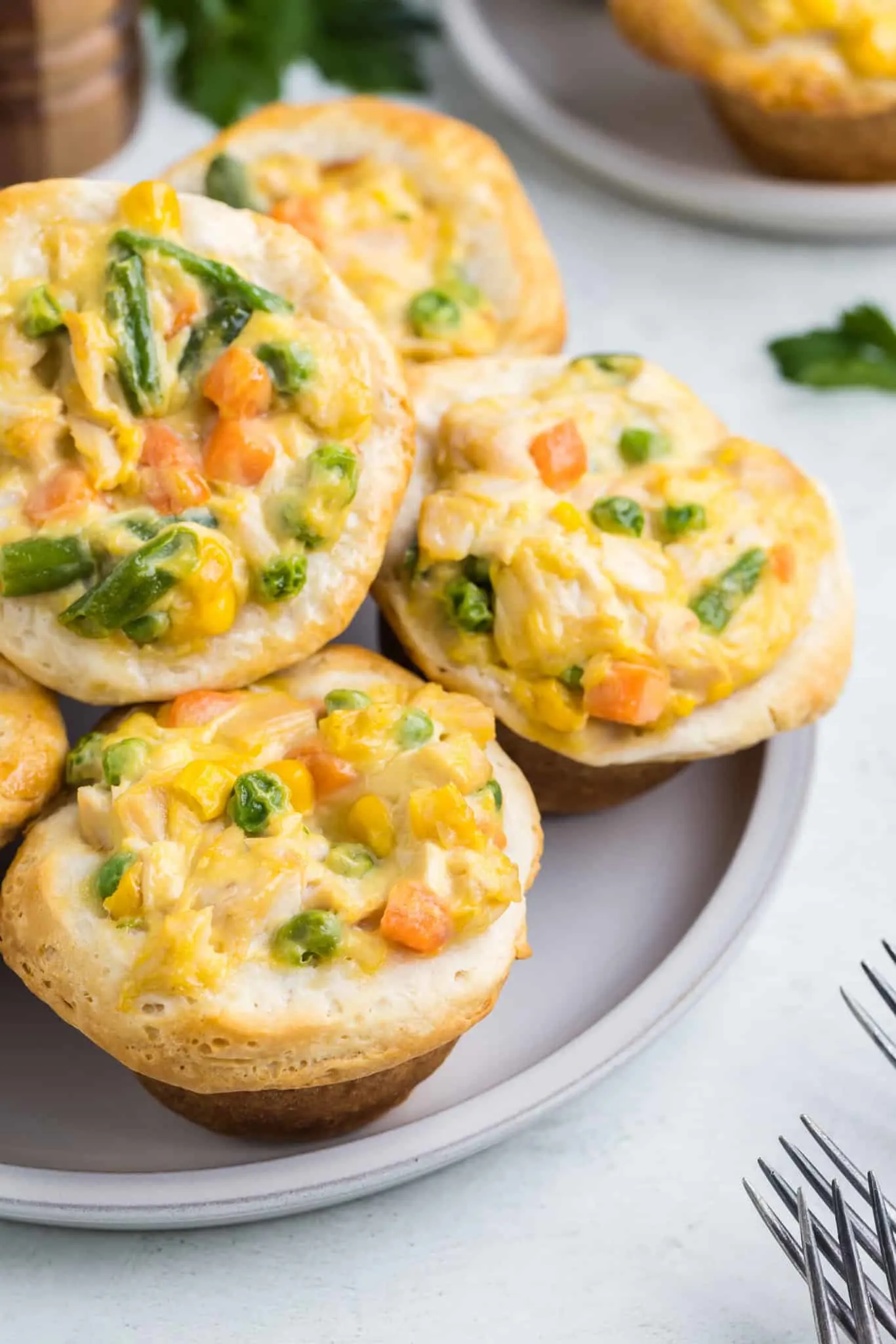 Mini Chicken Pot Pies are an easy dinner recipe using precooked chicken, frozen mixed vegetables, cream of chicken soup and Pillsbury refrigerated biscuits.