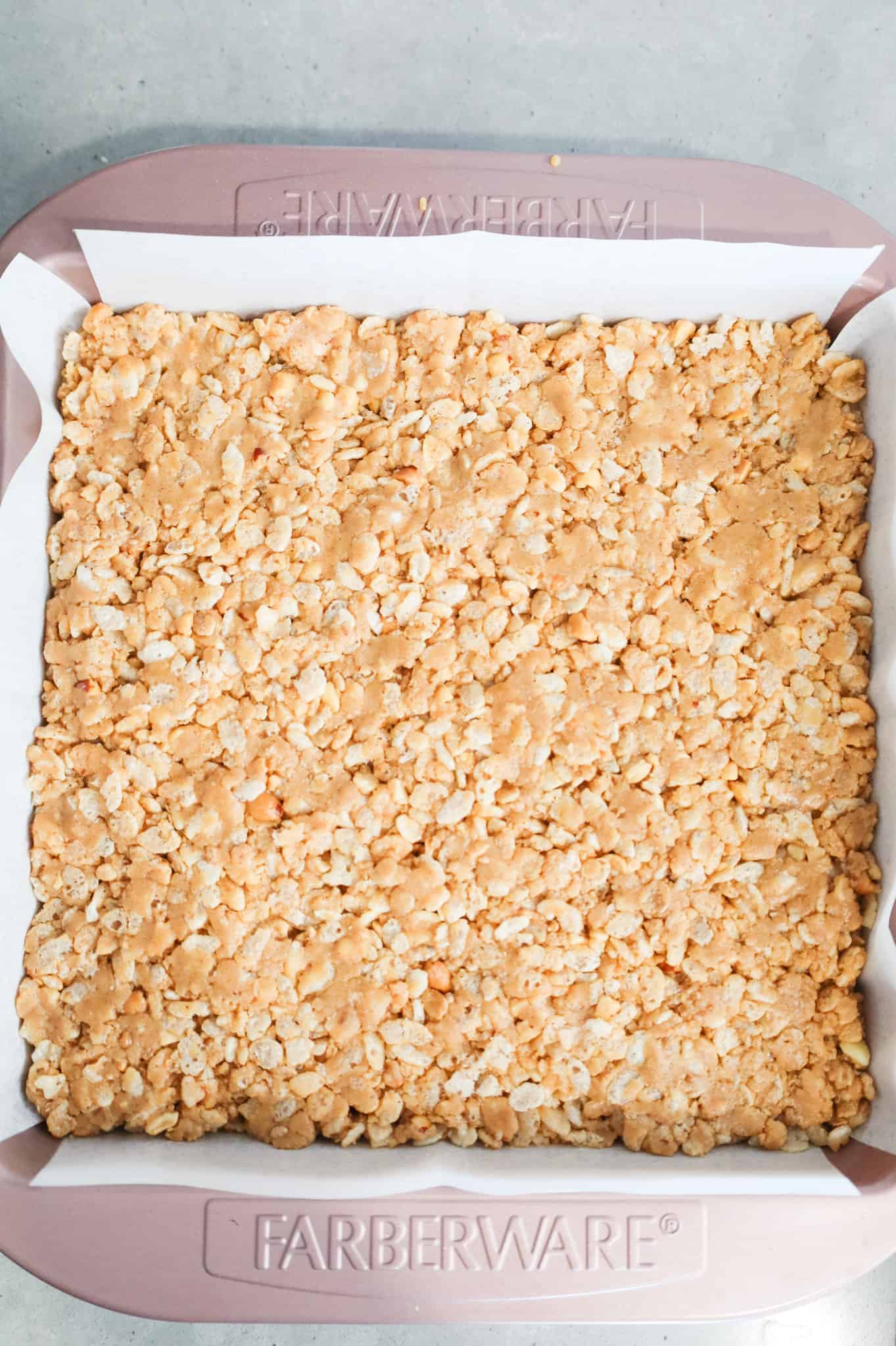 peanut butter rice krispie mixture in a parchment lined baking pan