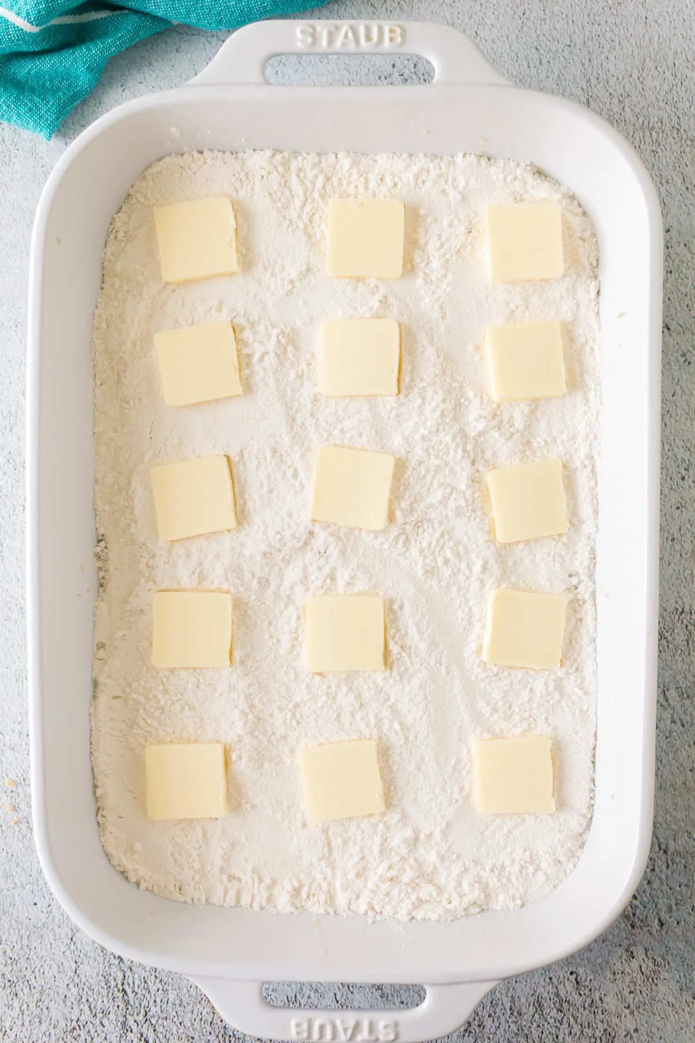 butter slices on top of white cake mix in a baking dish