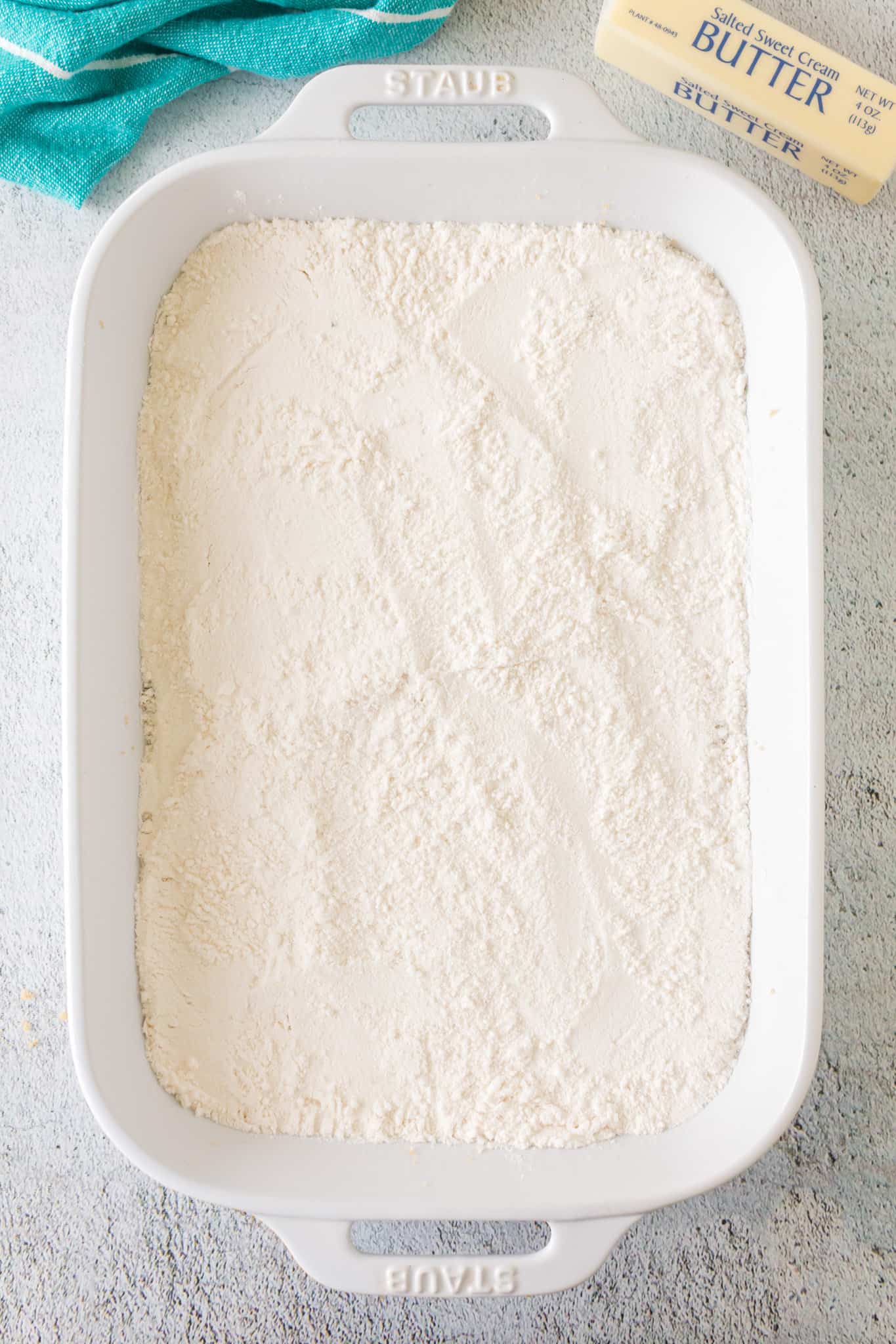 white cake mix on top of canned pineapple in a baking dish