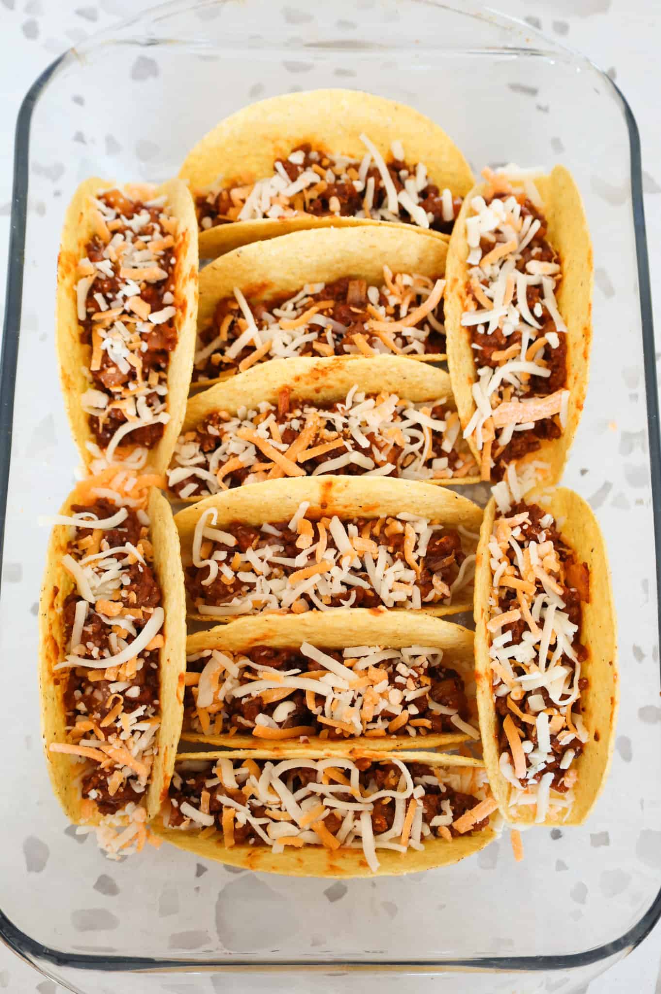 shredded cheese on top of ground beef mixture in taco shells