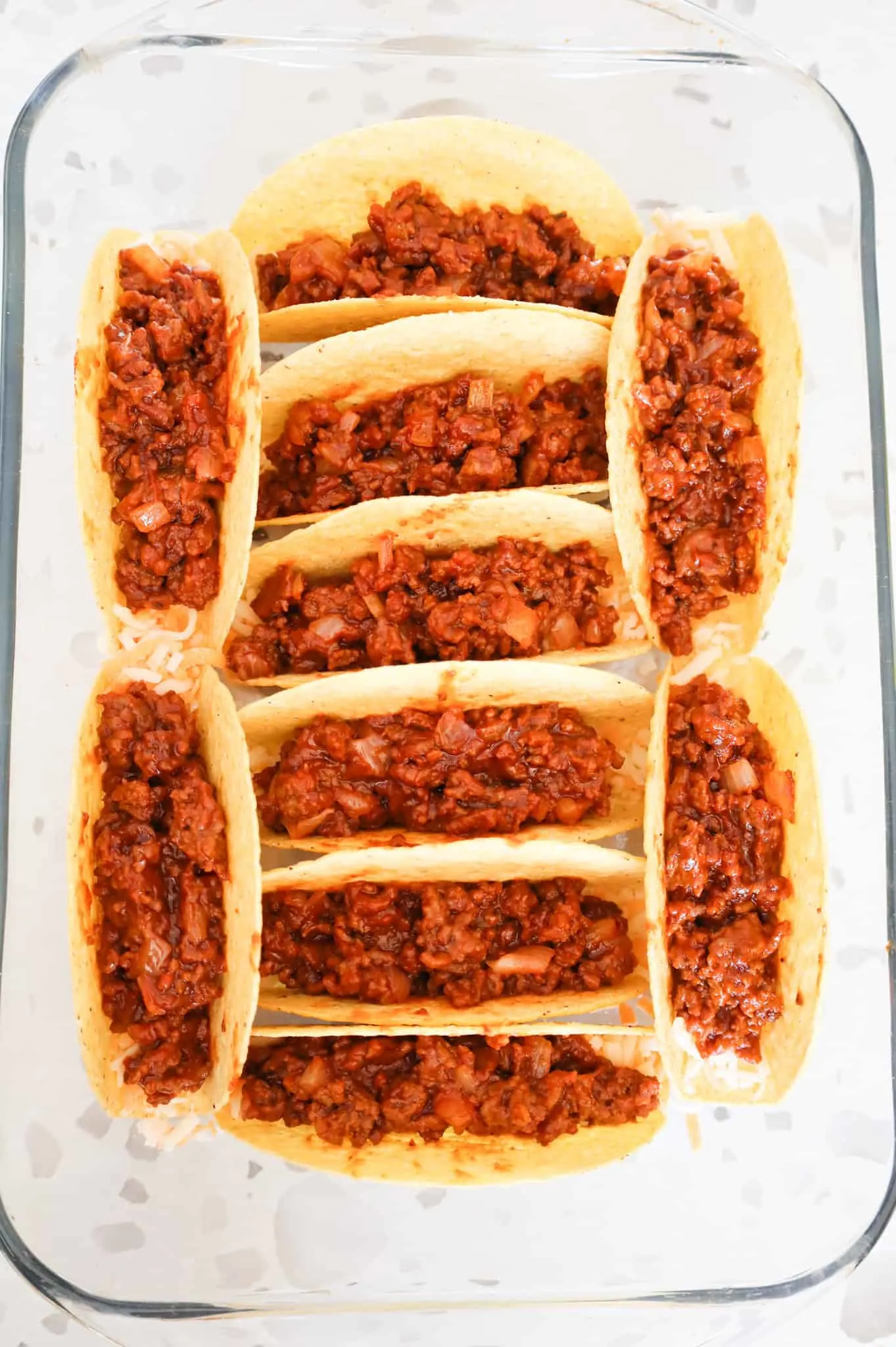 sloppy joe ground beef mixture in taco shells in a baking dish