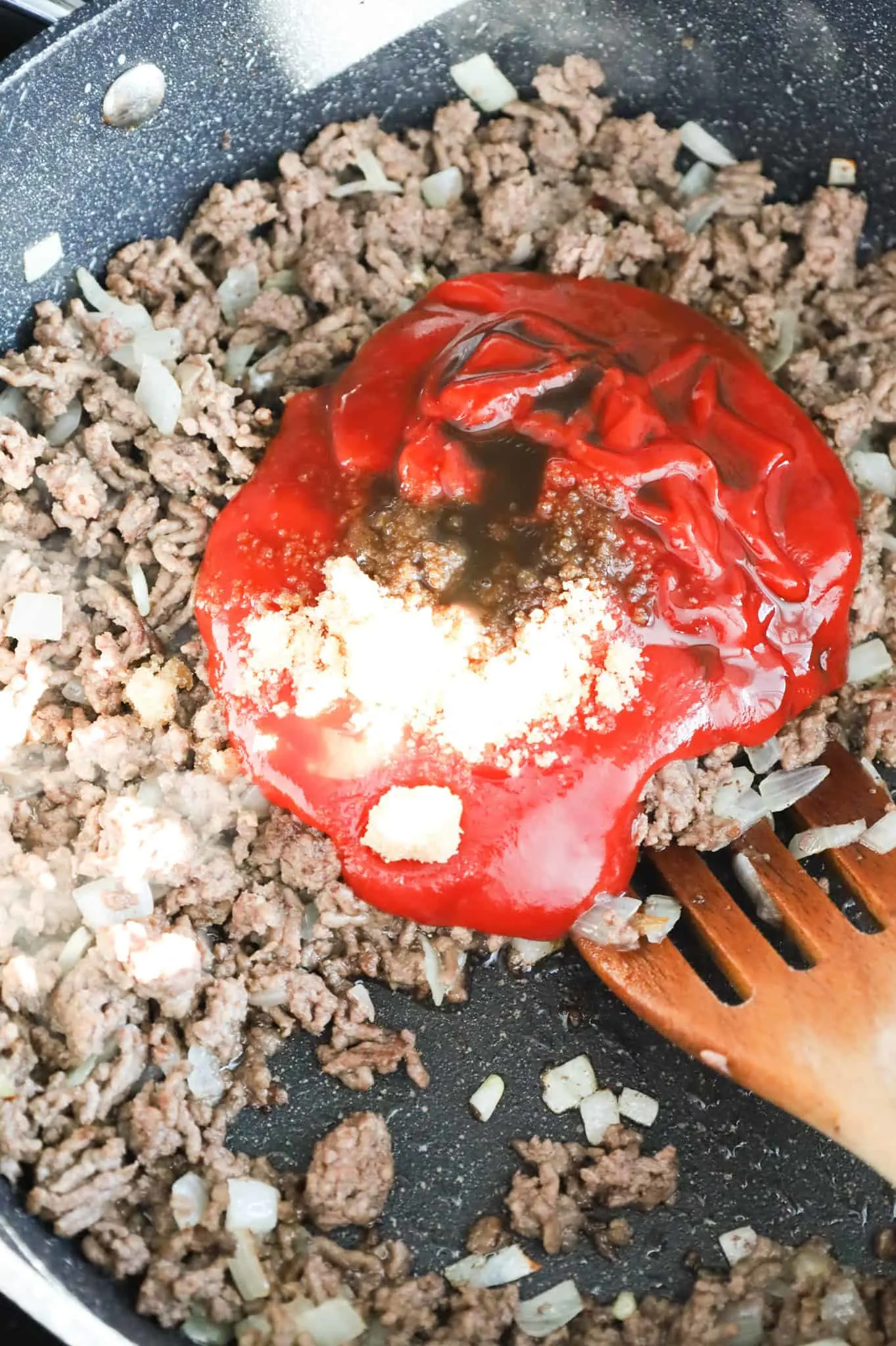 Worcestershire sauce, brown sugar and ketchup on top of ground beef in a skillet