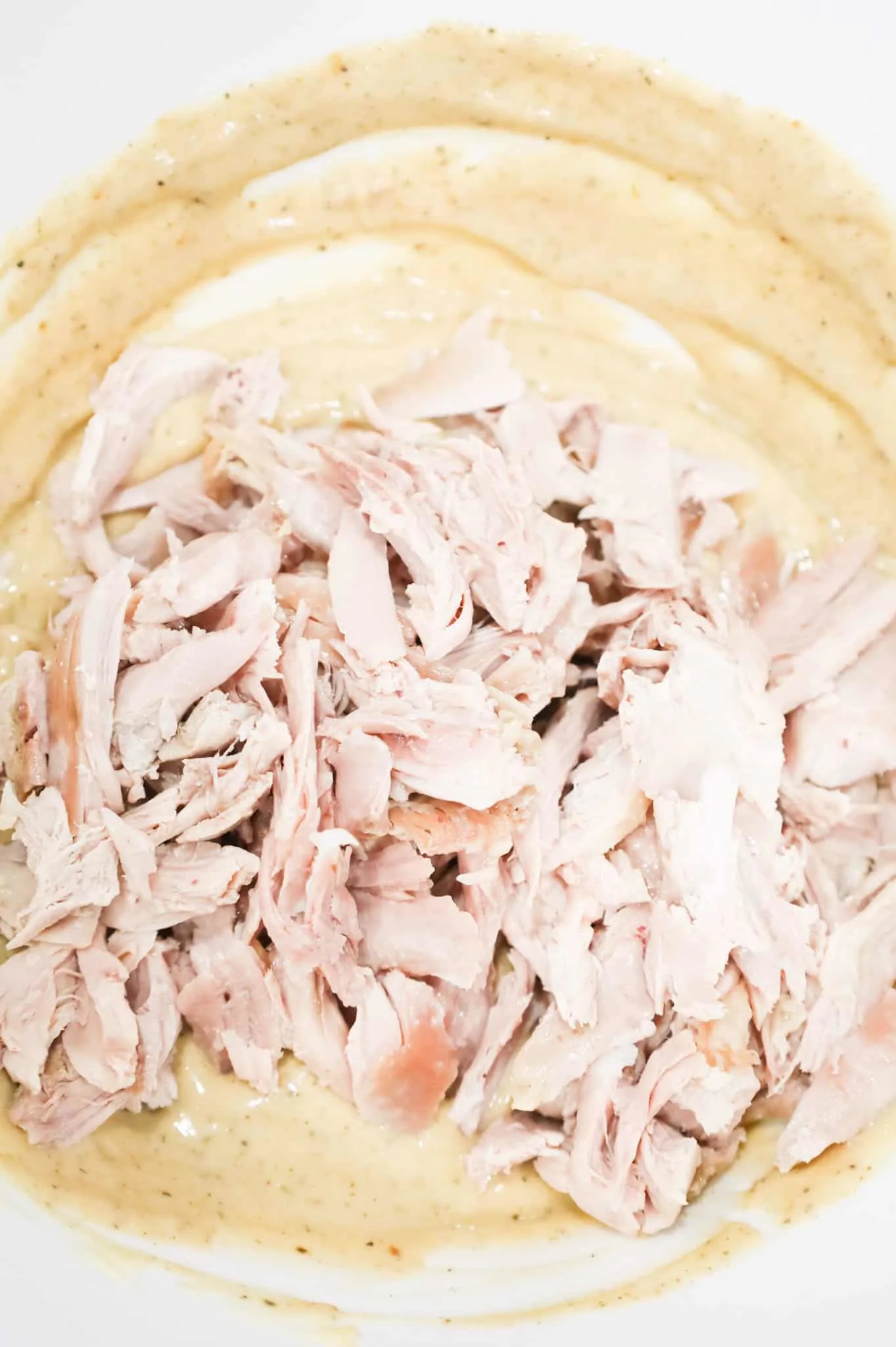 shredded turkey on top of soup mixture in a mixing bowl