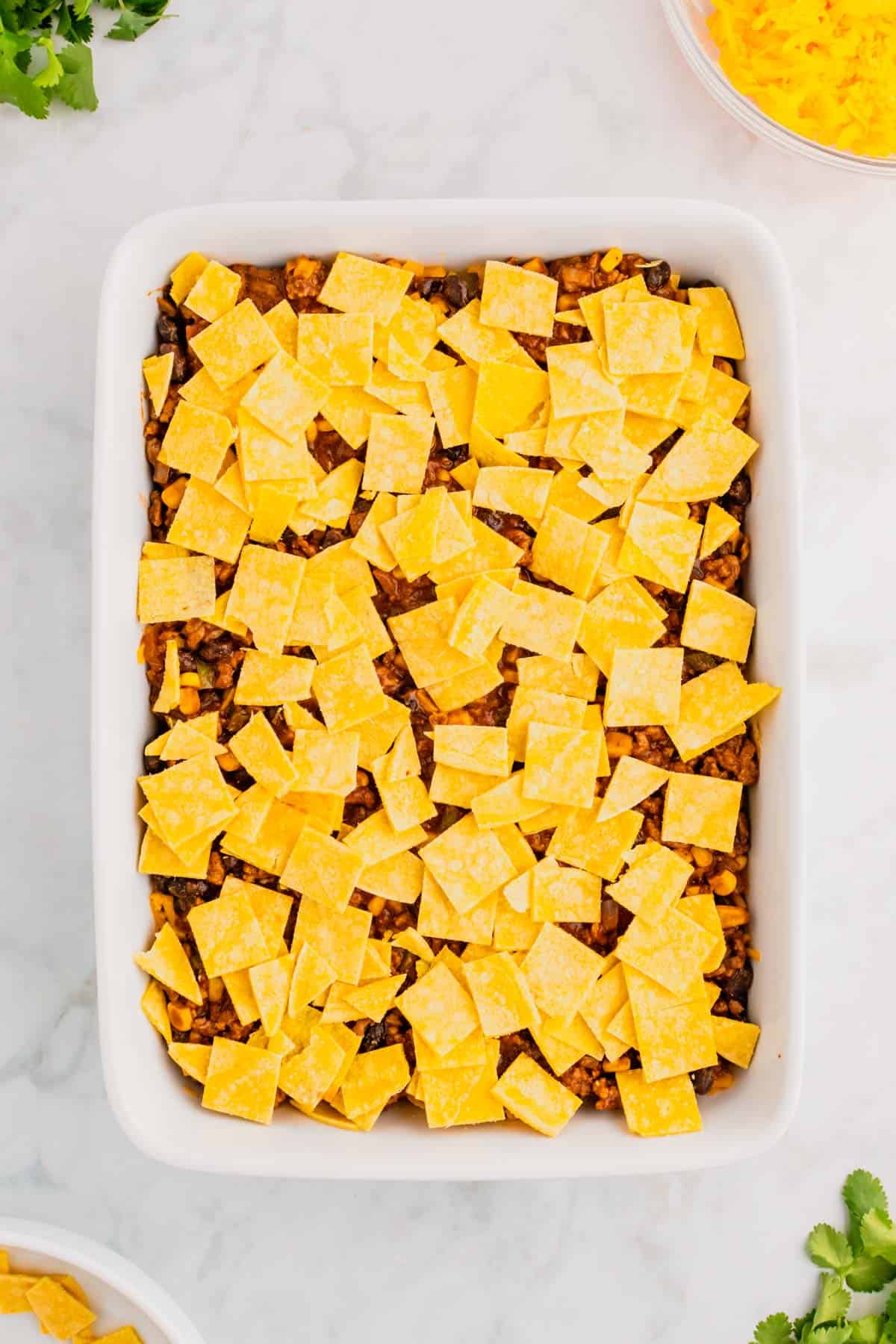 corn tortilla pieces on top of ground beef mixture in a baking dish