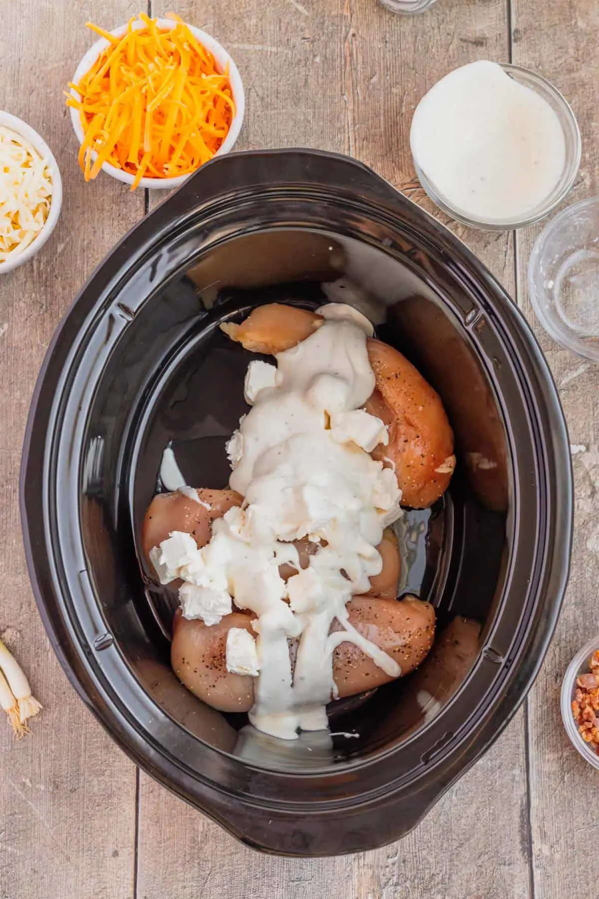 ranch dressing and cubes of cream cheese on top of chicken breasts in a slow cooker