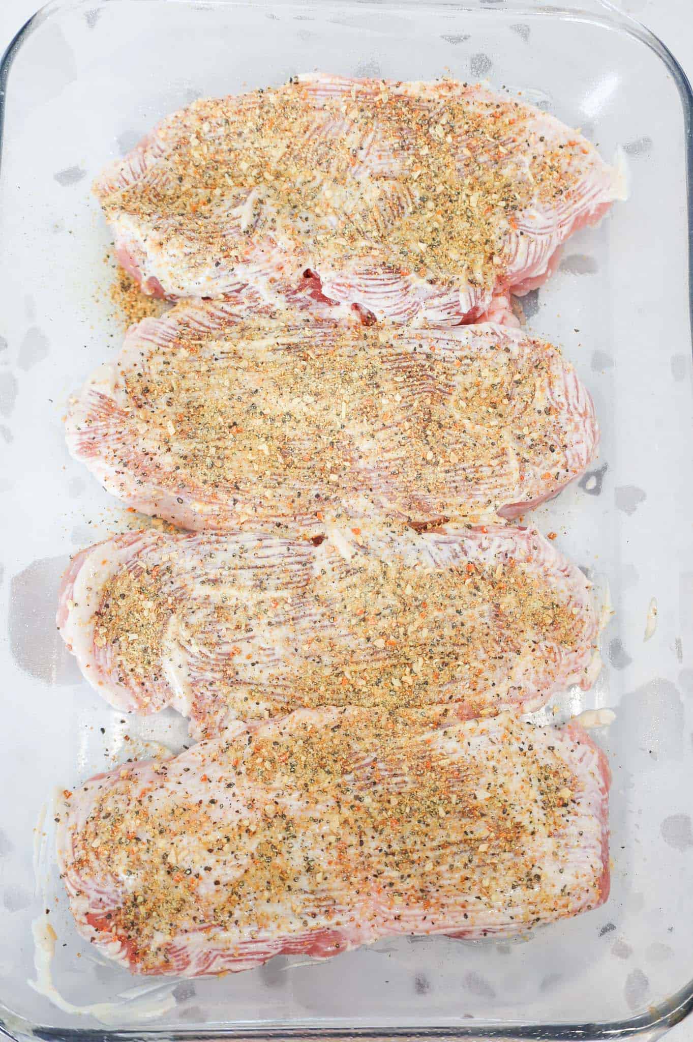 lemon pepper and mayo mixture on top of pork chops in a baking dish