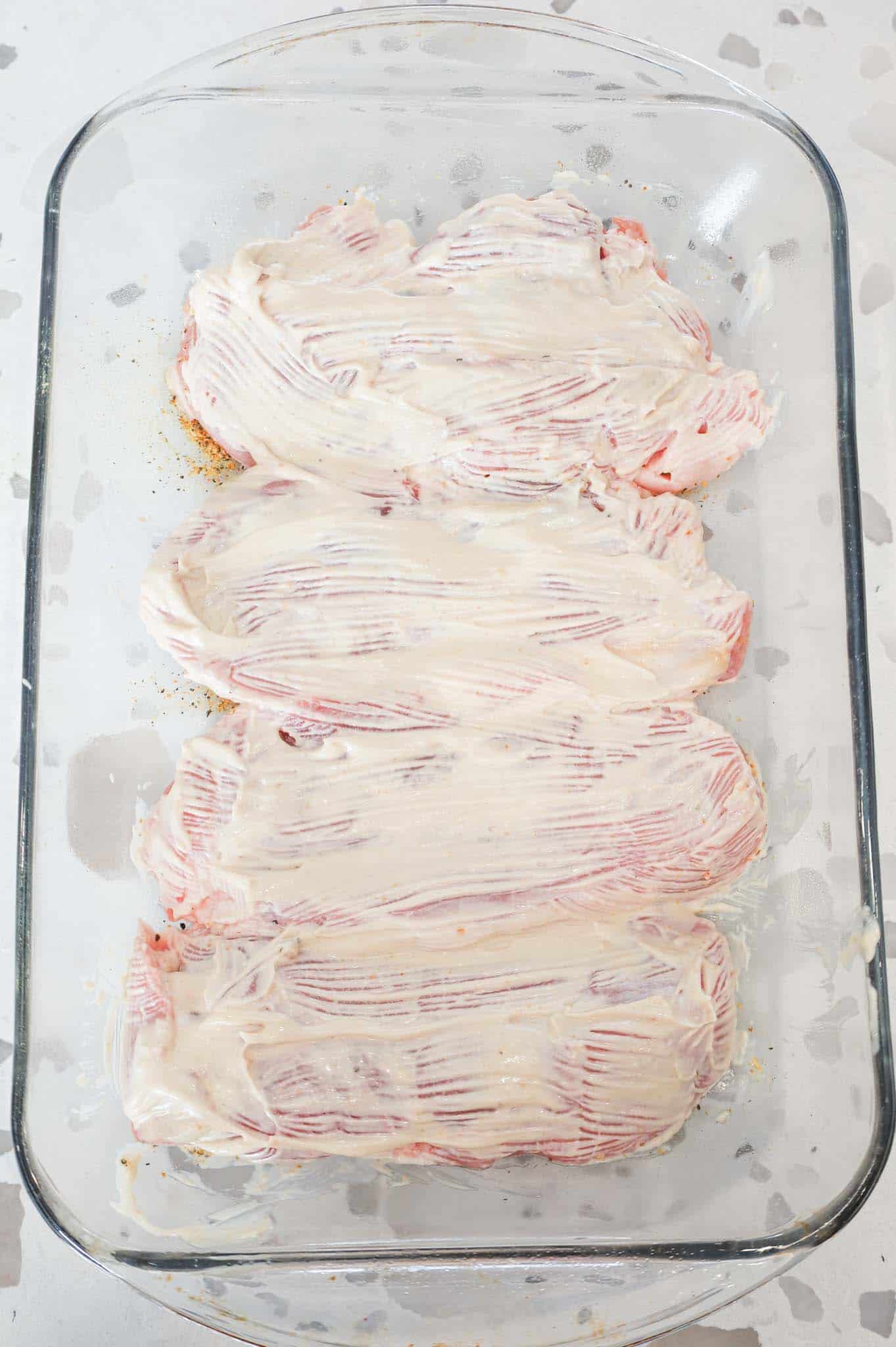 pork chops coated in mayo mixture in a baking dish