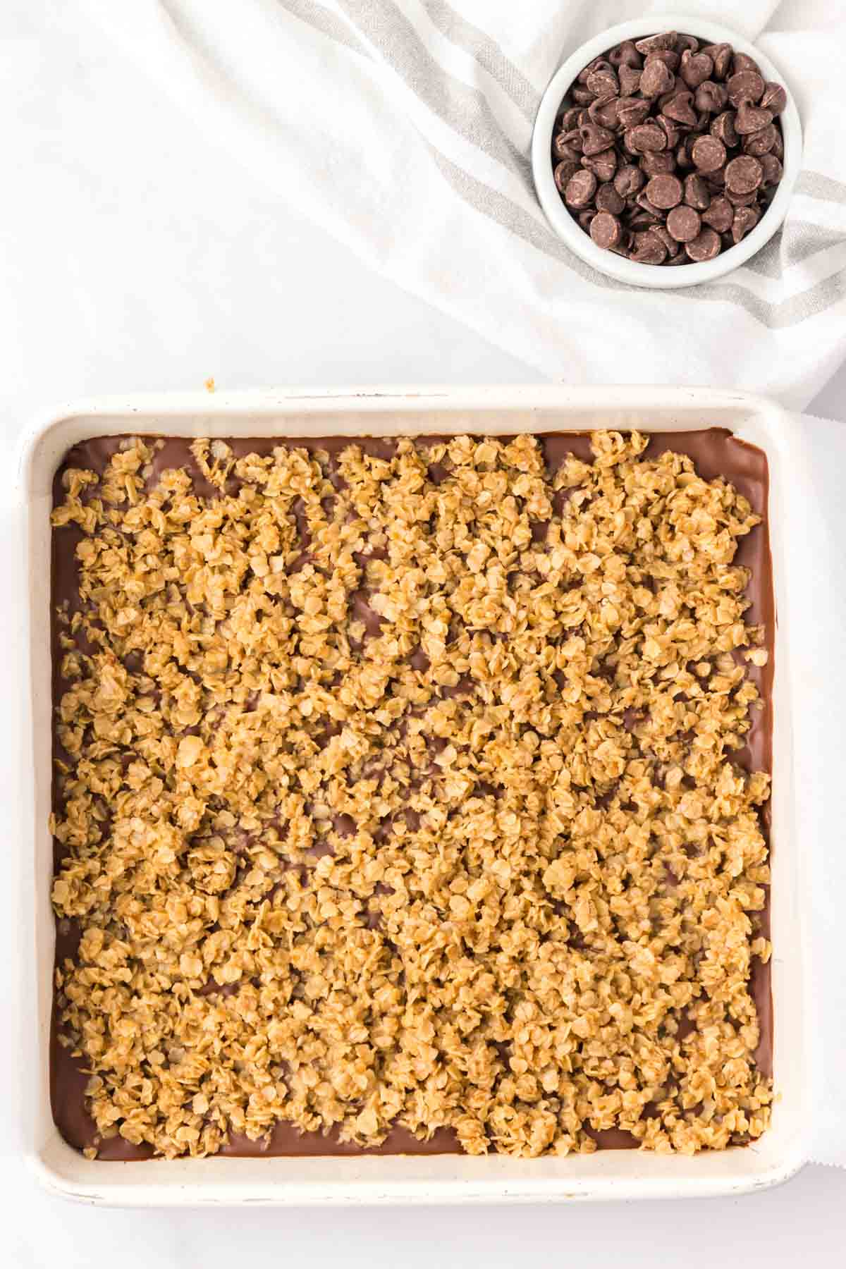oat mixture sprinkled on top of chocolate peanut butter layer in a baking dish
