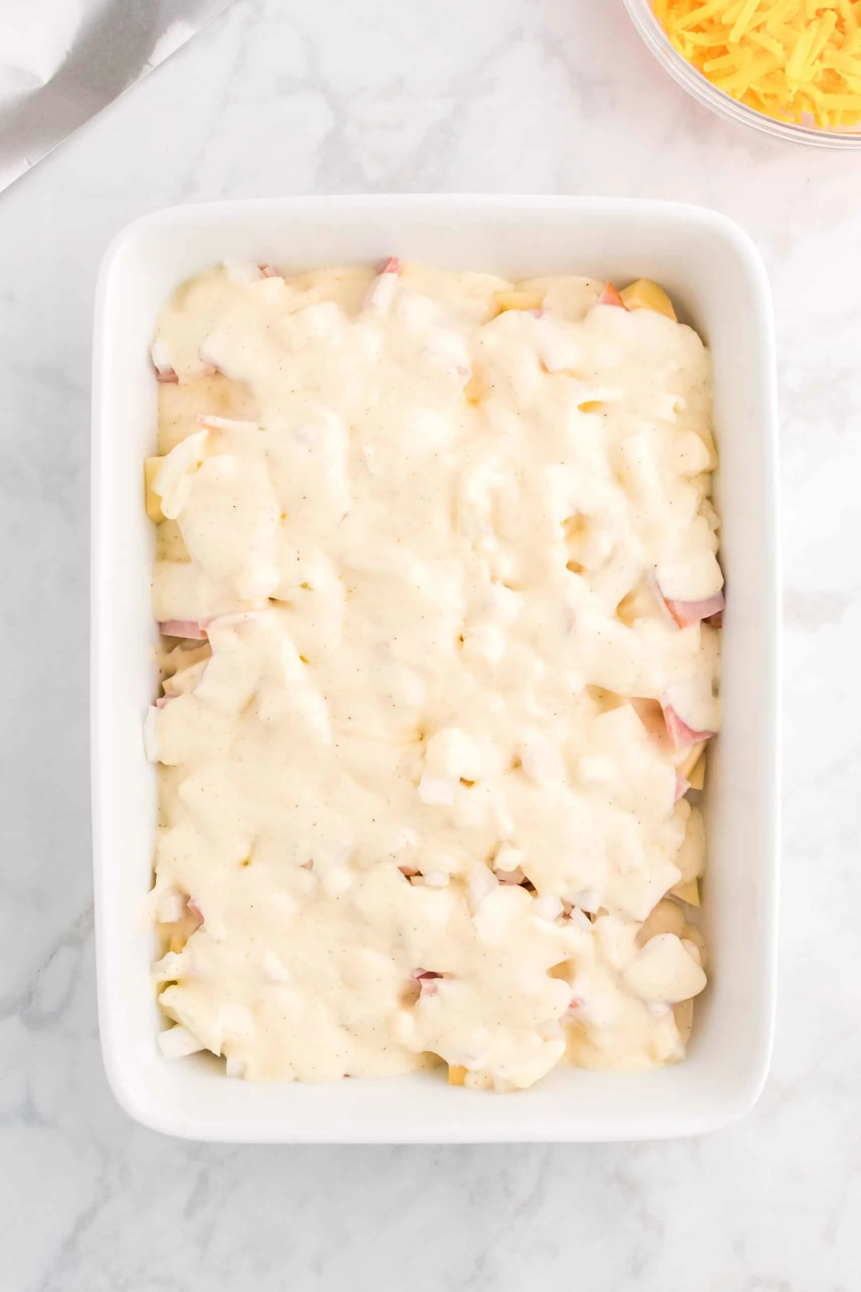 creamy soup mixture poured over ham and potatoes in a baking dish