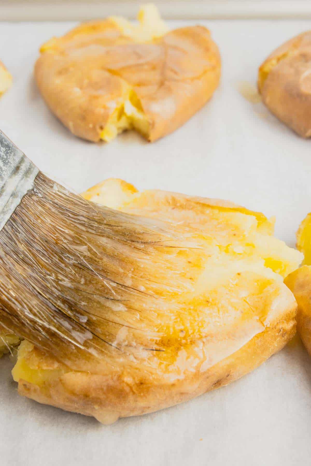 brushing smashed potatoes with melted butter