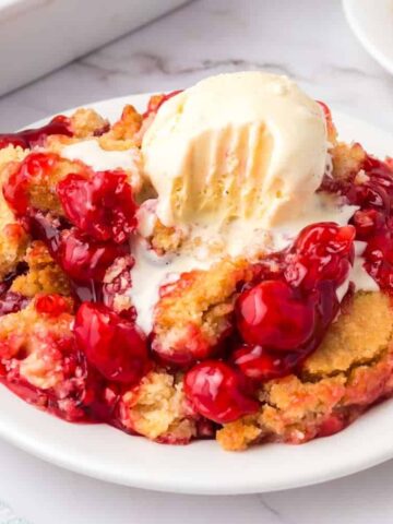Cherry Dump Cake is an easy dessert recipe made with cherry pie filling, vanilla cake mix, crumbled butter cookies, vanilla extract and butter.