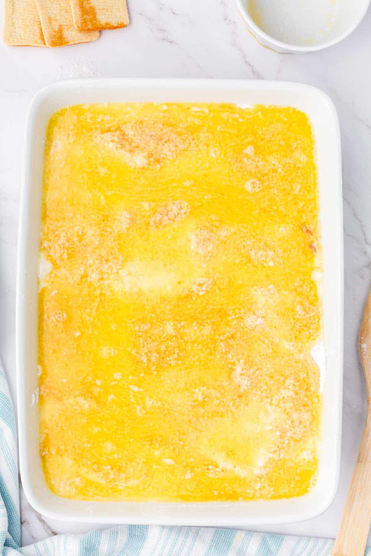 melted butter on top of cake mix and cookie crumbs in a baking dish