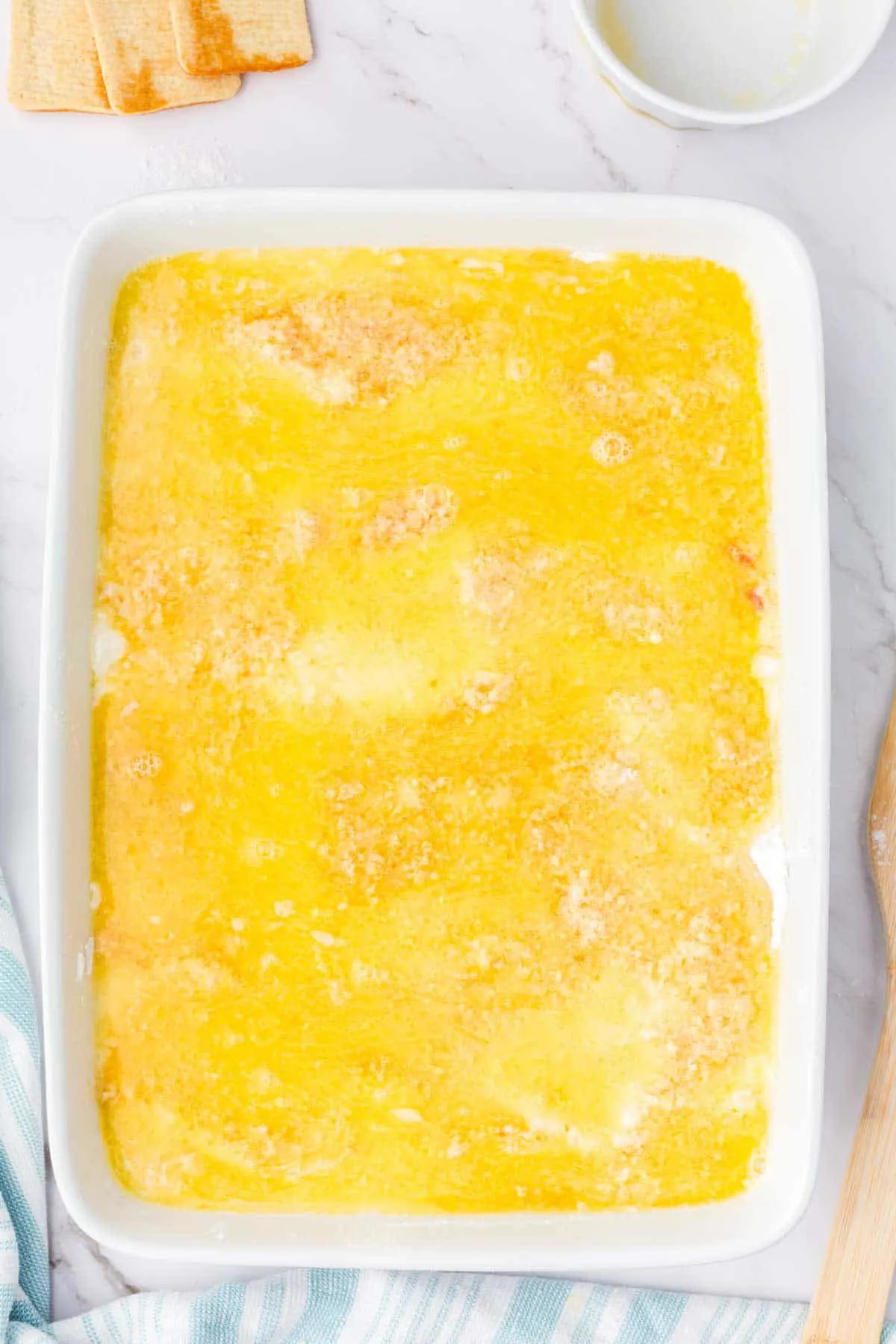 melted butter on top of cake mix and cookie crumbs in a baking dish
