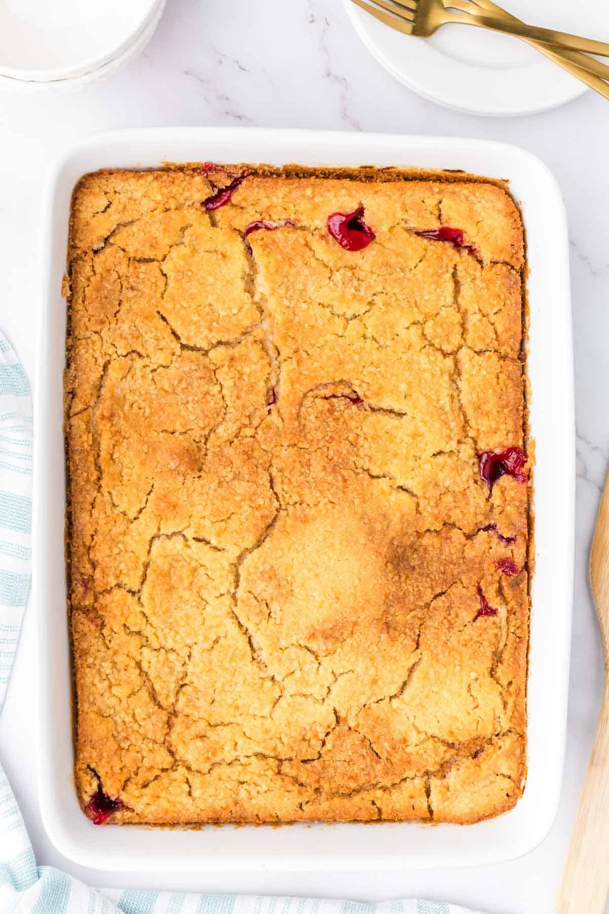 Cherry Dump Cake is an easy dessert recipe made with cherry pie filling, vanilla cake mix, crumbled butter cookies, vanilla extract and butter.