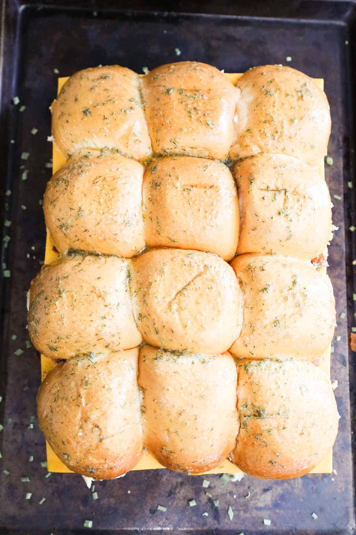 chicken sliders on a baking sheet brushed with seasoned butter