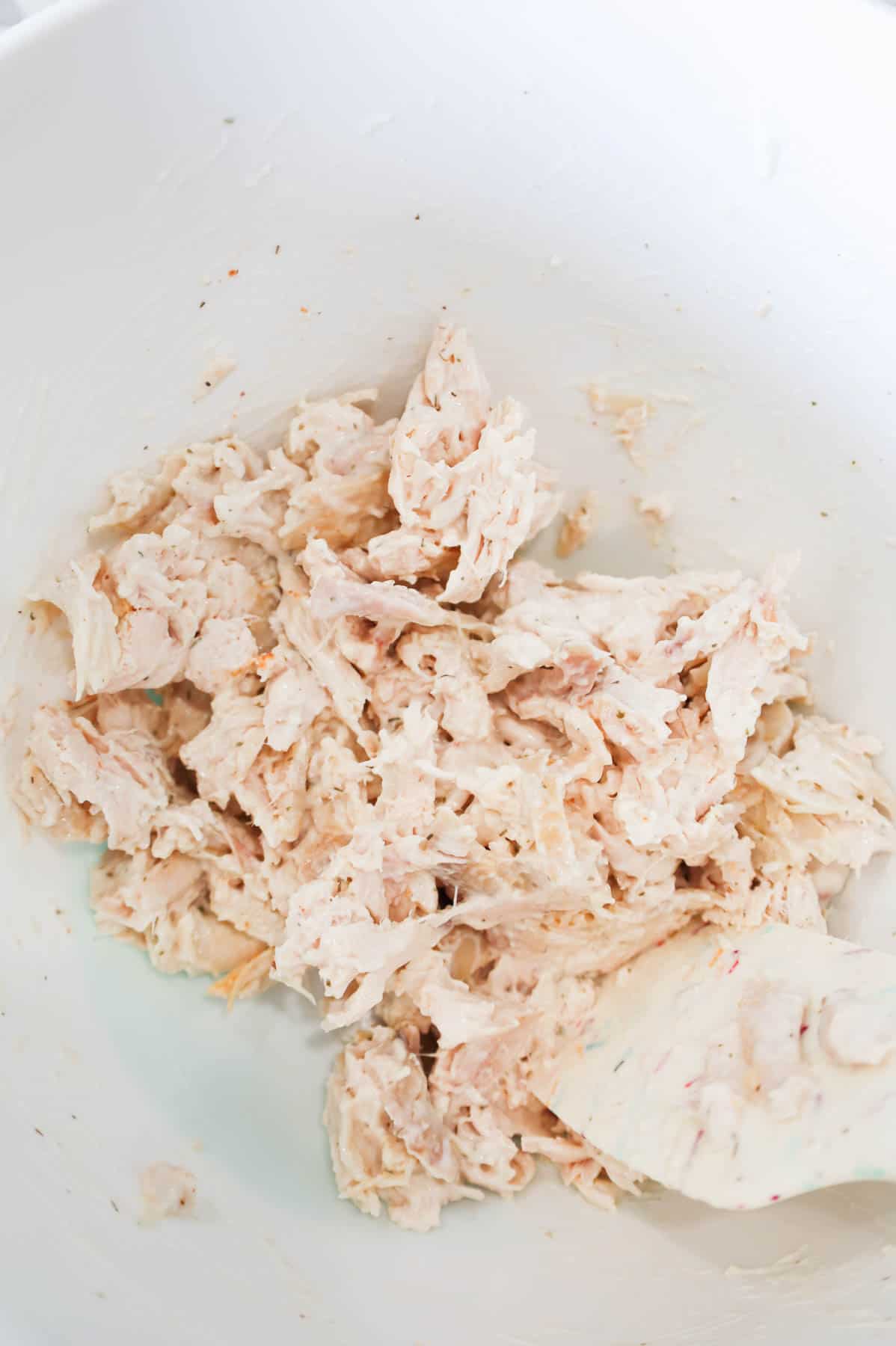 shredded chicken coated with ranch dressing in a mixing bowl