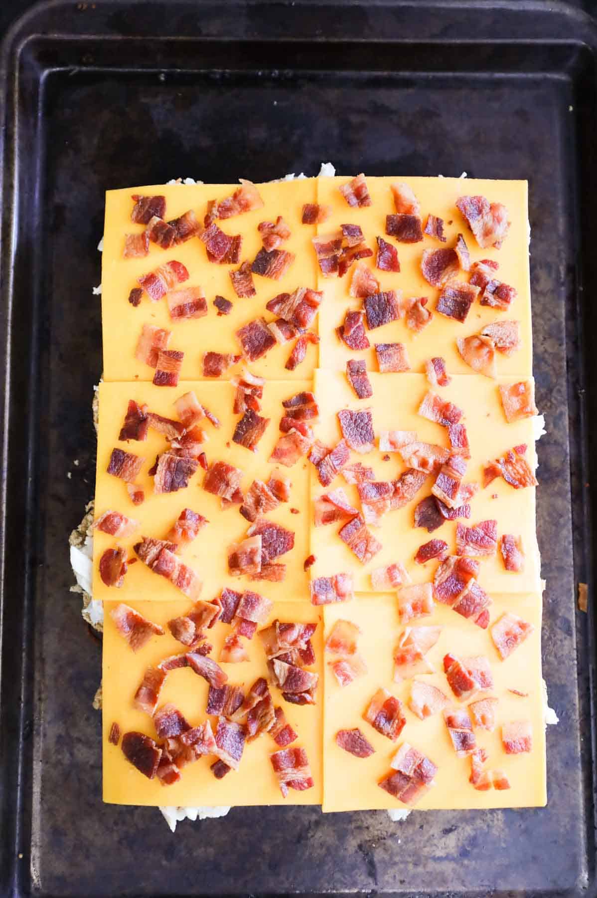crumbled bacon on top of cheddar cheese slices on slider rolls