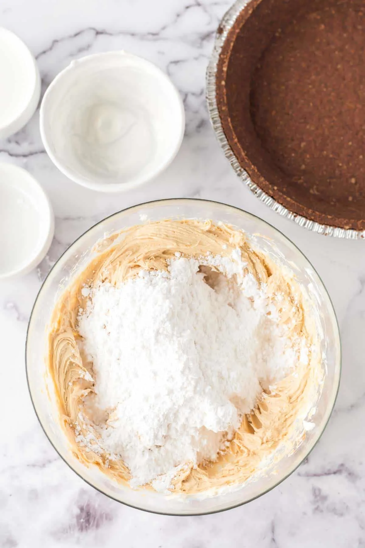 powdered sugar on top of creamy peanut butter mixture in a bowl