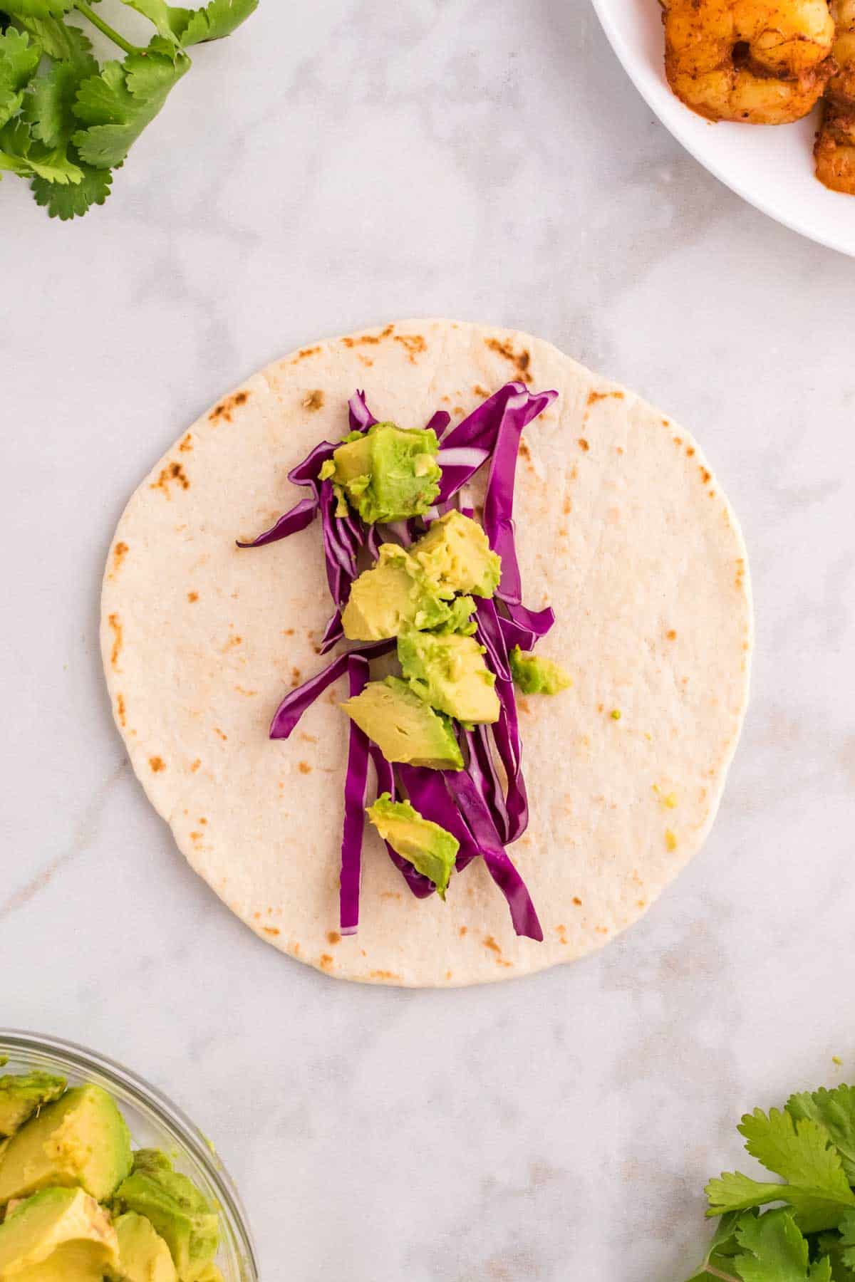 diced avocado and sliced red cabbage on a flour tortilla