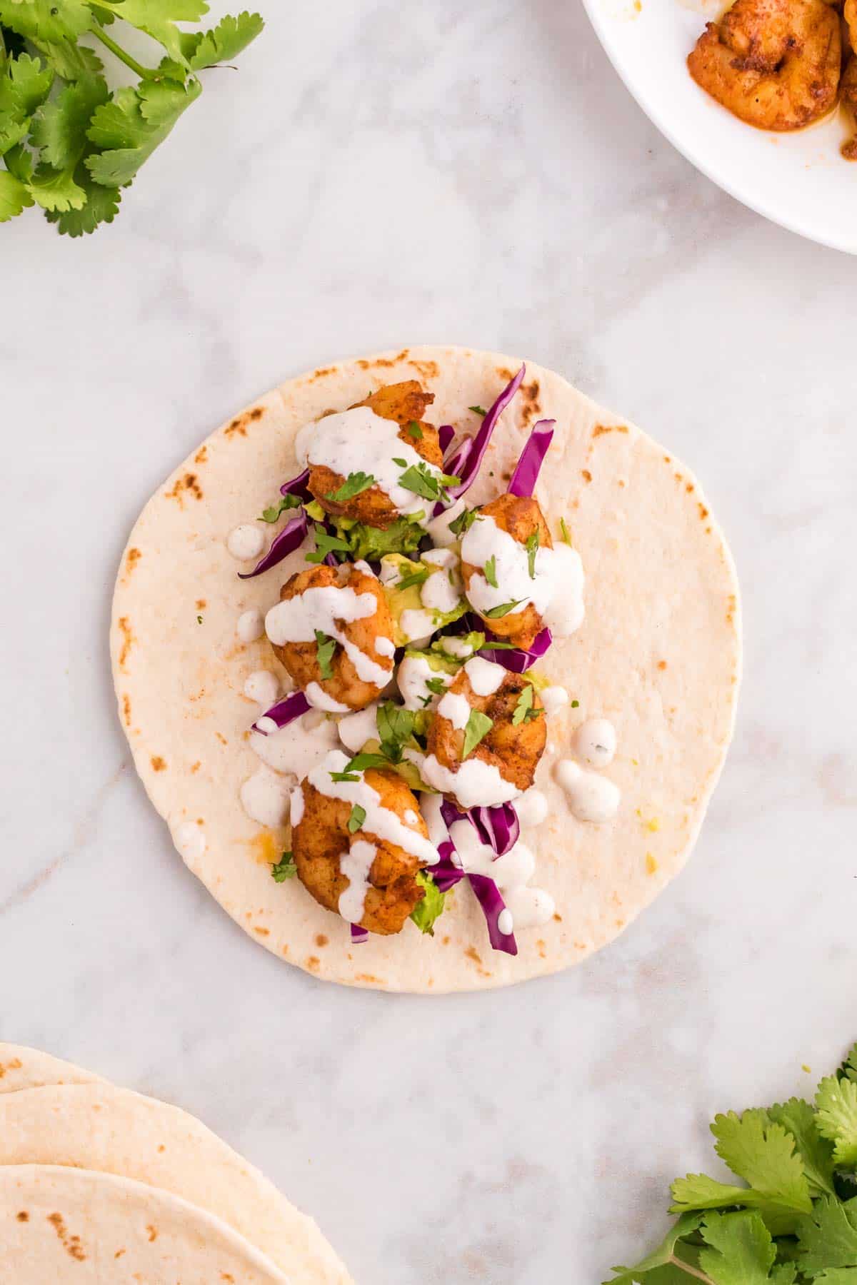 Cilantro Lime Shrimp Tacos are tasty tacos with seasoned shrimp, sliced red cabbage, diced avocados and a creamy dressing made with mayo, Greek yogurt, lime juice and cilantro.