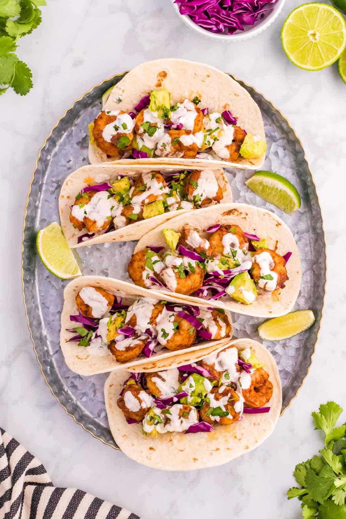 Cilantro Lime Shrimp Tacos are tasty tacos with seasoned shrimp, sliced red cabbage, diced avocados and a creamy dressing made with mayo, Greek yogurt, lime juice and cilantro.