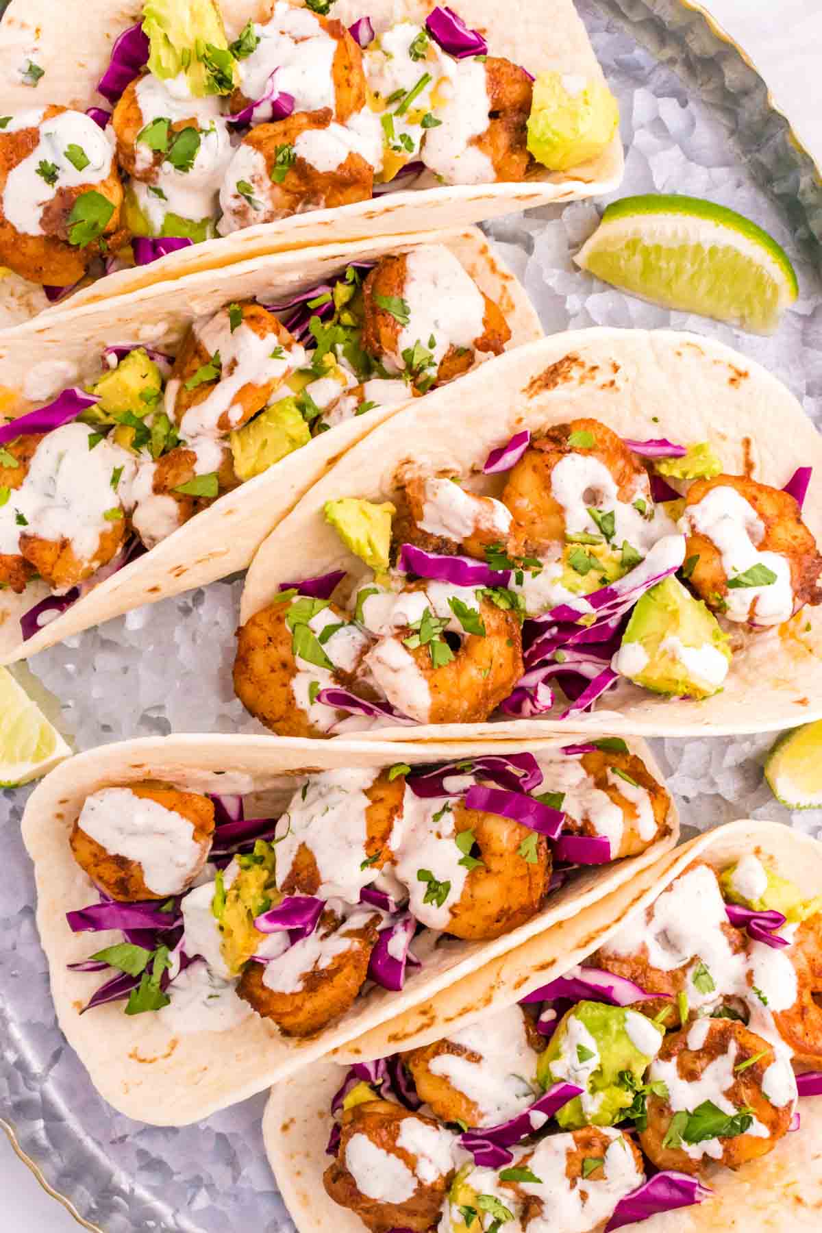 Cilantro Lime Shrimp Tacos are tasty tacos with seasoned shrimp, sliced red cabbage, diced avocados and a creamy dressing made with mayo, Greek yogurt, lime juice and cilantro.