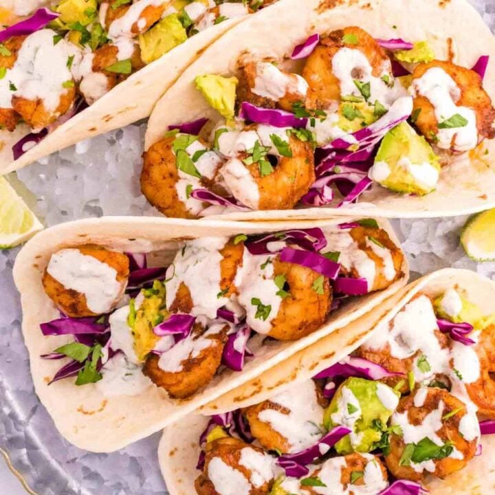 Cilantro Lime Shrimp Tacos are tasty tacos with seasoned shrimp, sliced red cabbage, diced avocados and a creamy dressing made with mayo, Greek yogurt, lime juice and cilantro.